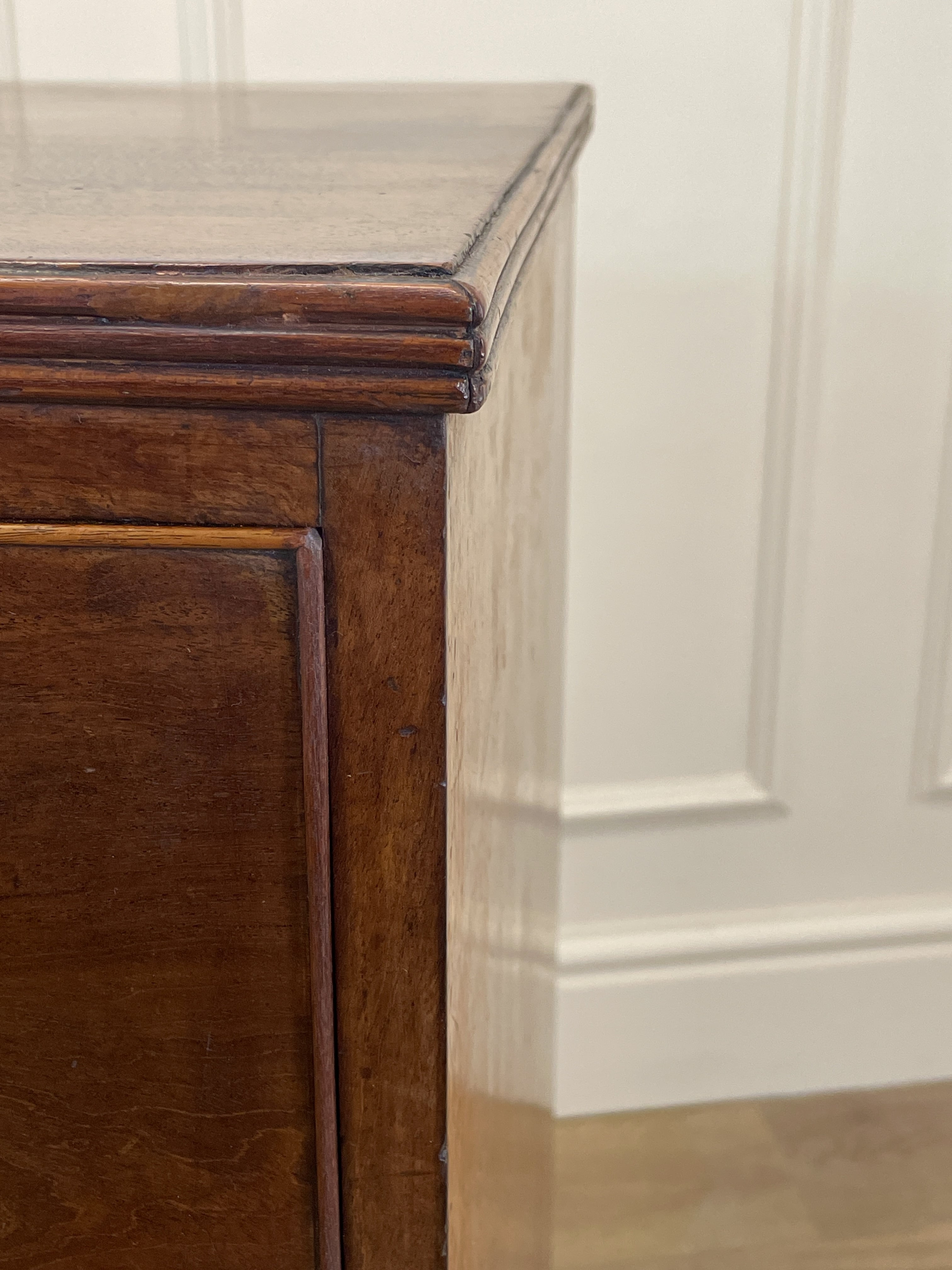 Close-up of a wooden cabinet corner with a white wall background