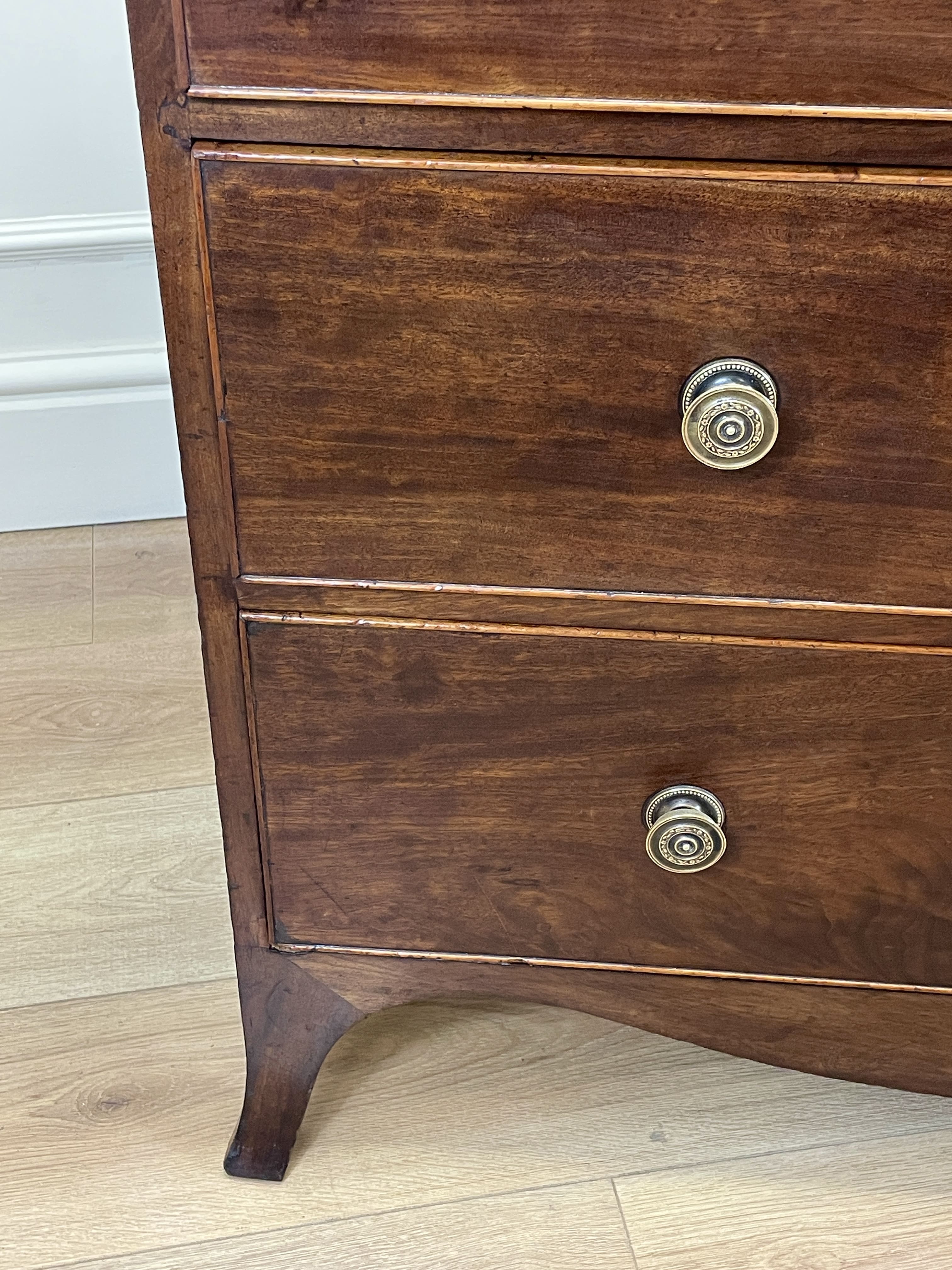Wooden dresser with brass knobs on a wooden floor.