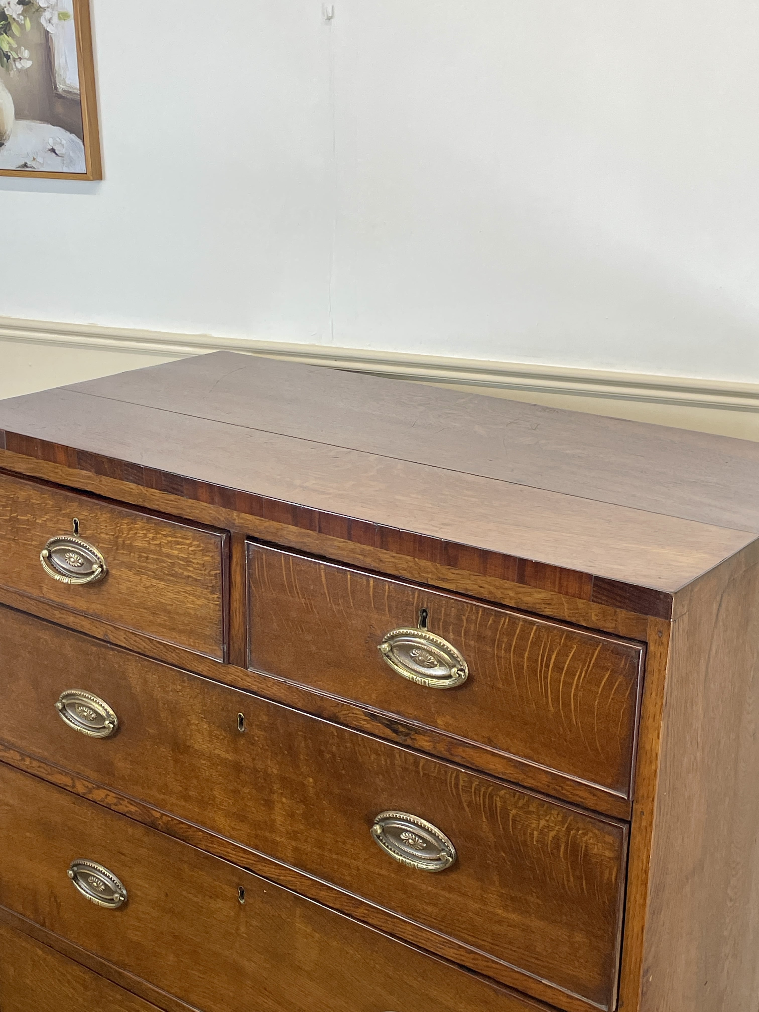 Wooden dresser with brass handles on a white wall background