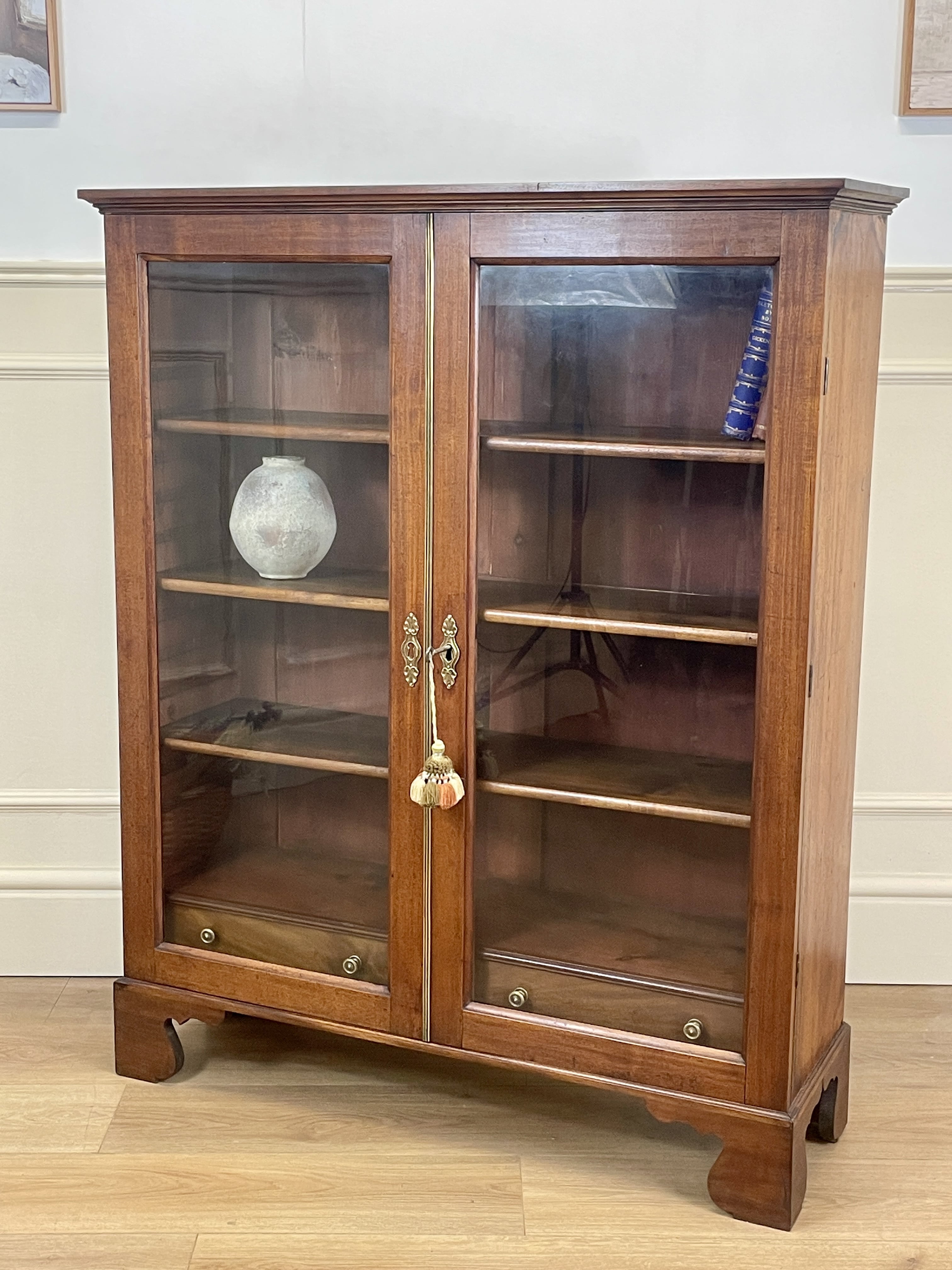 Wooden display cabinet with glass doors on a wooden floor.