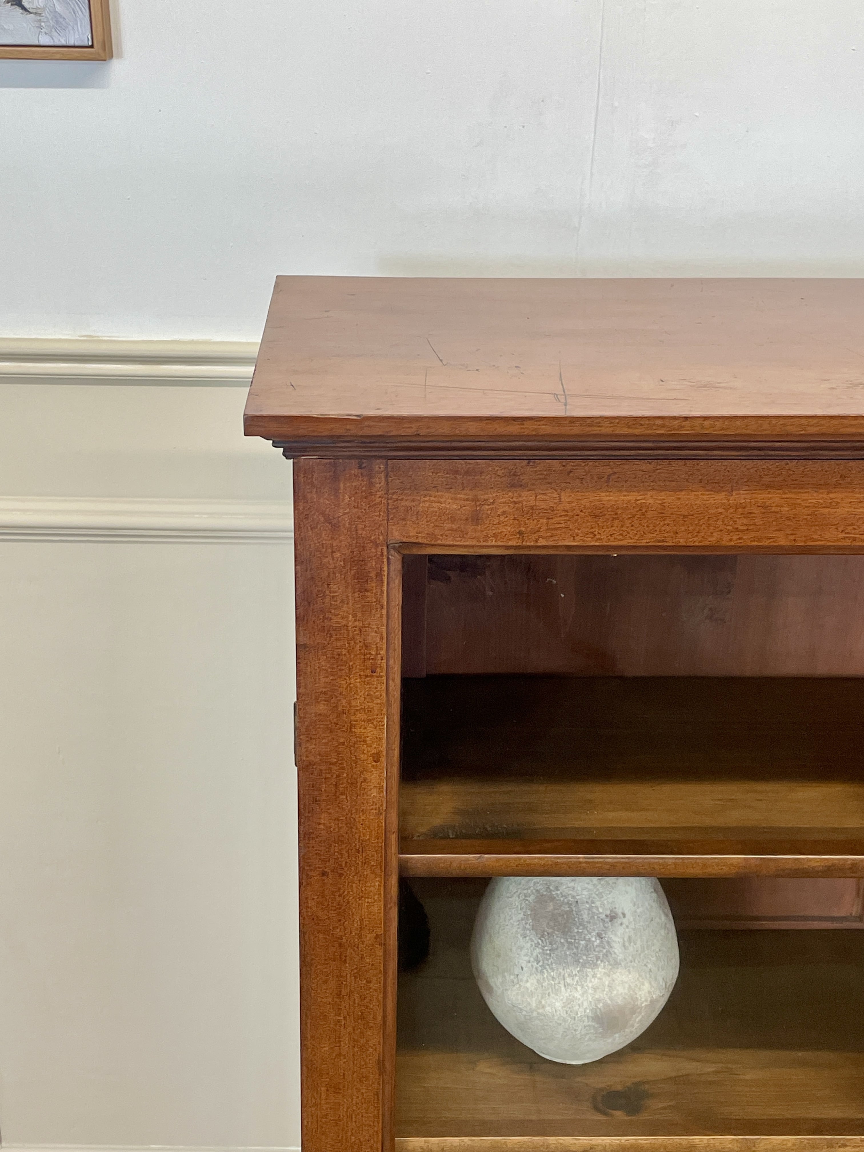 Wooden shelf with a white vase on a plain wall background