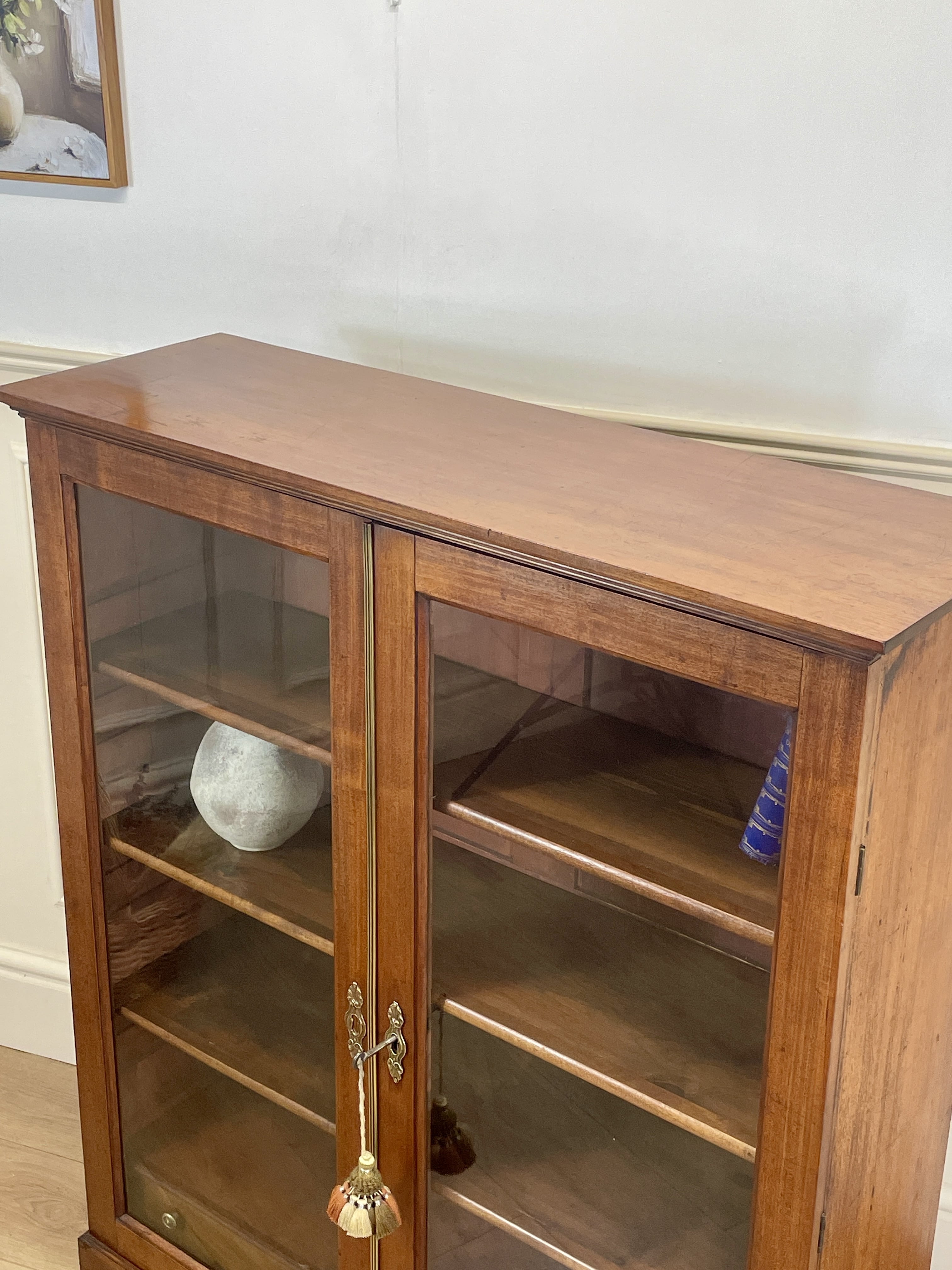 Wooden cabinet with glass doors against a white wall