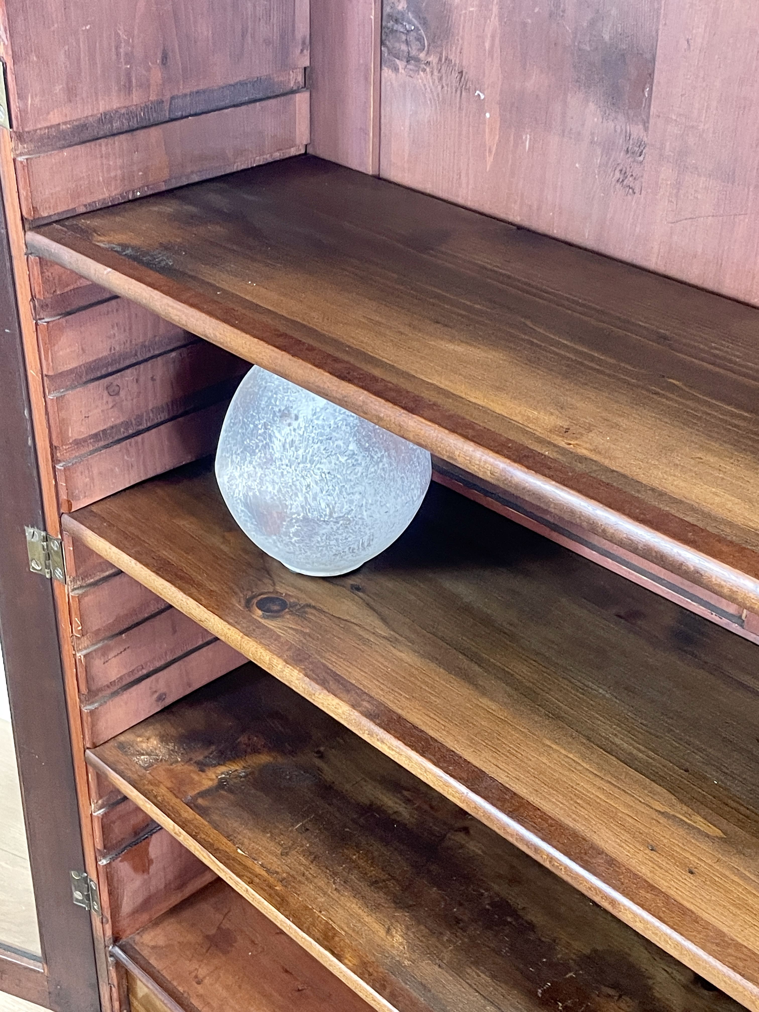 Wooden cabinet with a round glass object on one of the shelves