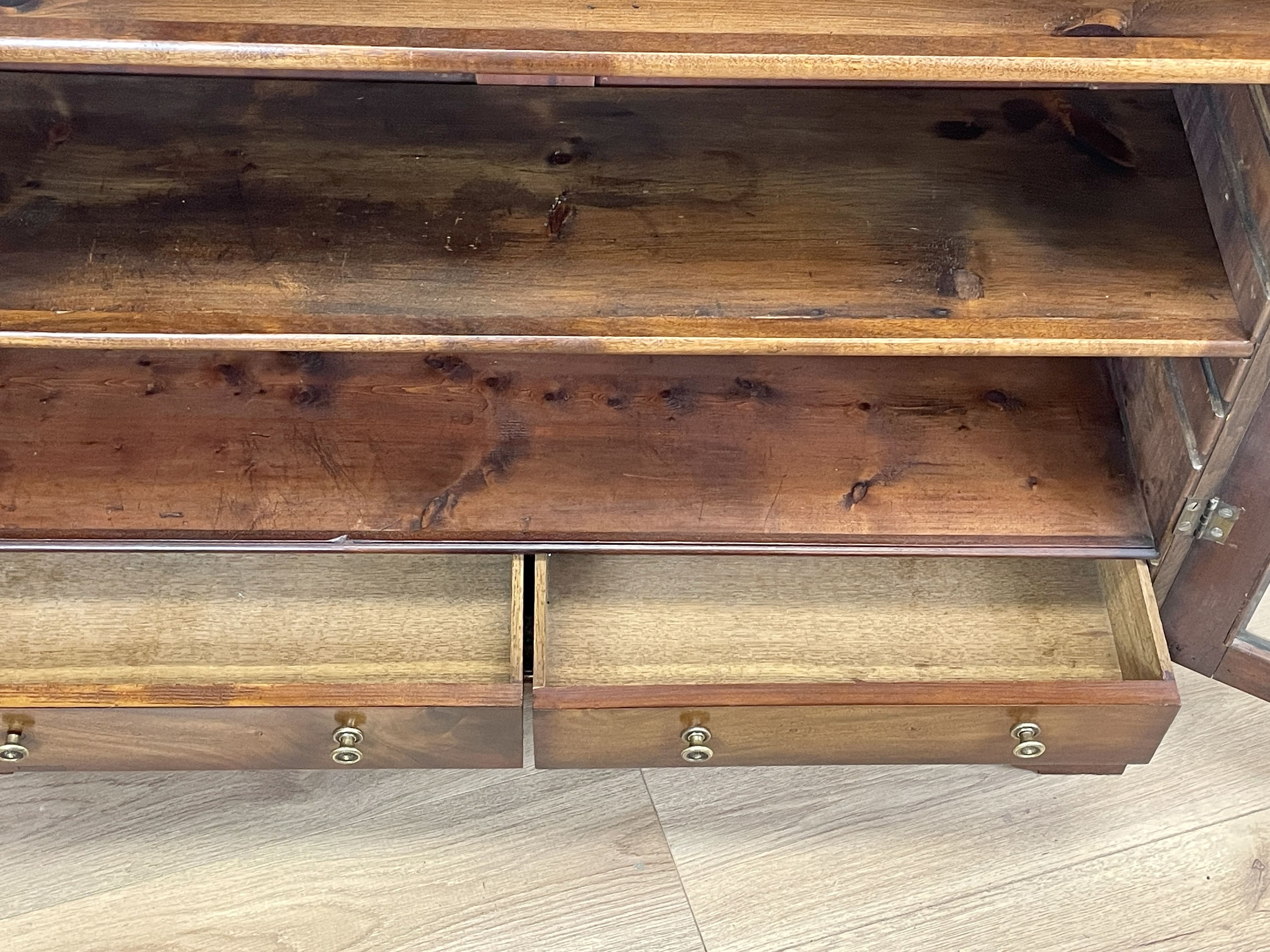 Wooden cabinet with open doors showing wooden shelves and drawers.