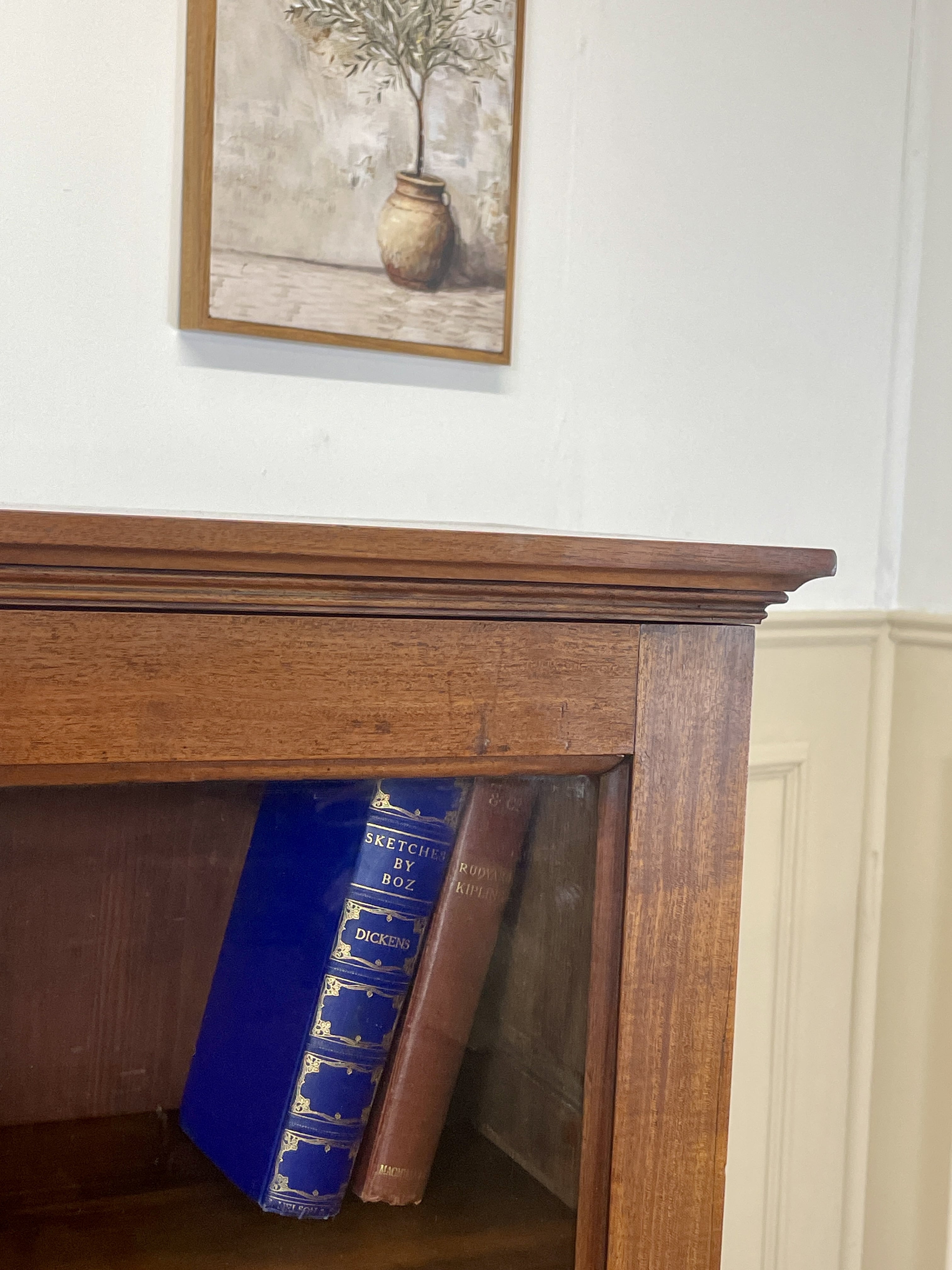 Wooden fireplace with two books inside, framed picture above on white wall