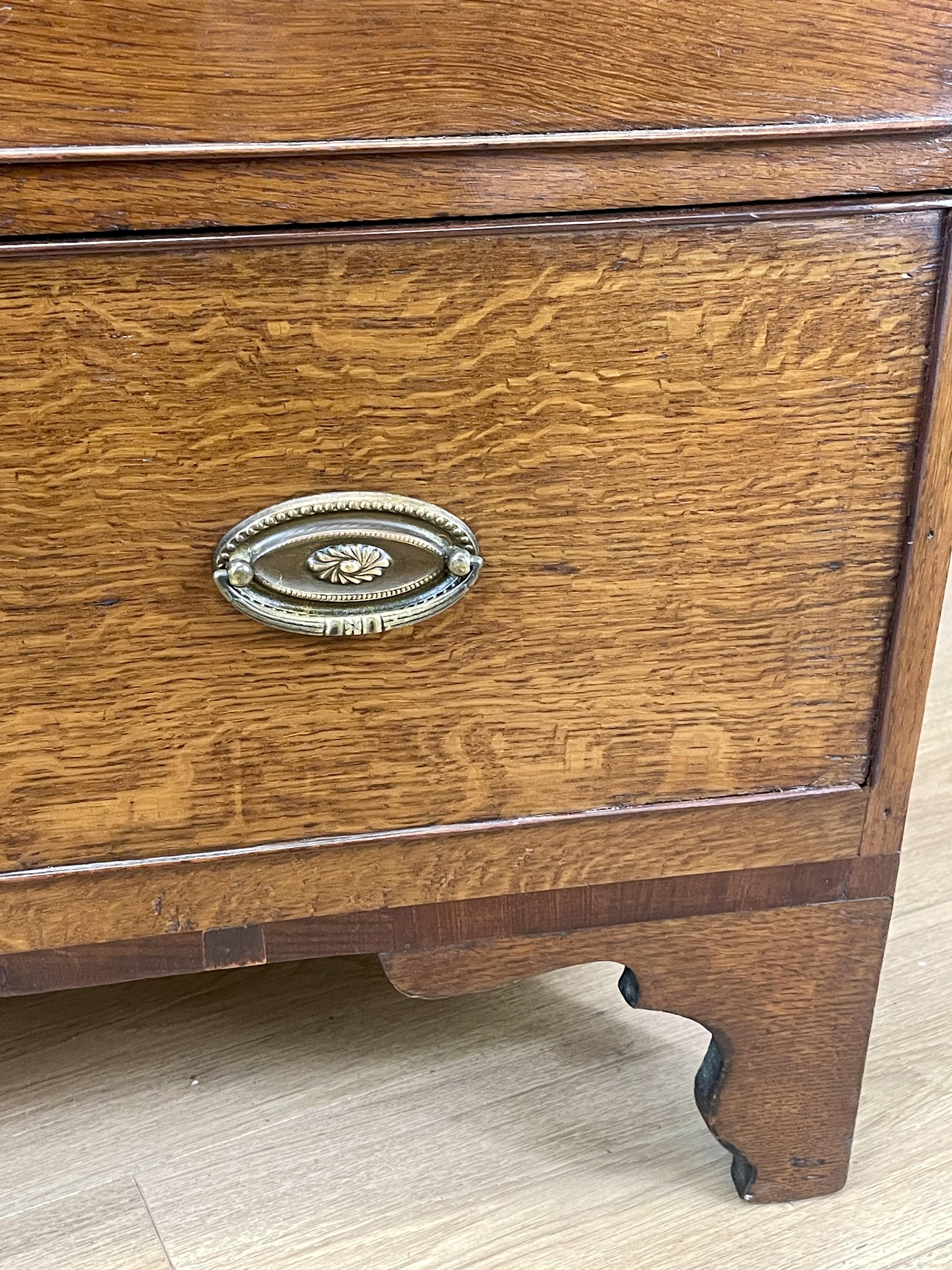 Wooden drawer with a decorative metal handle on a light wooden floor.