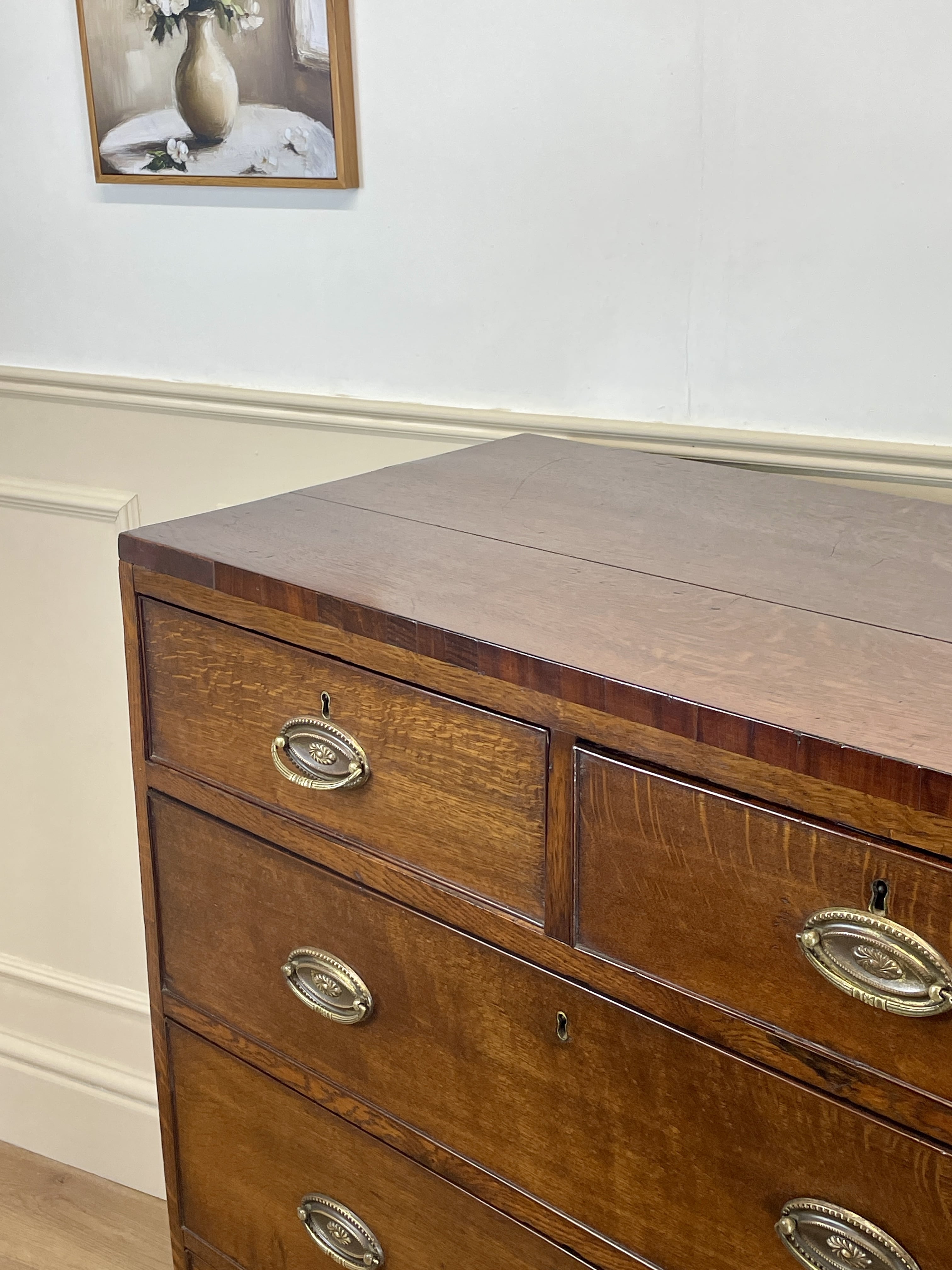 Wooden dresser with brass handles against a white wall