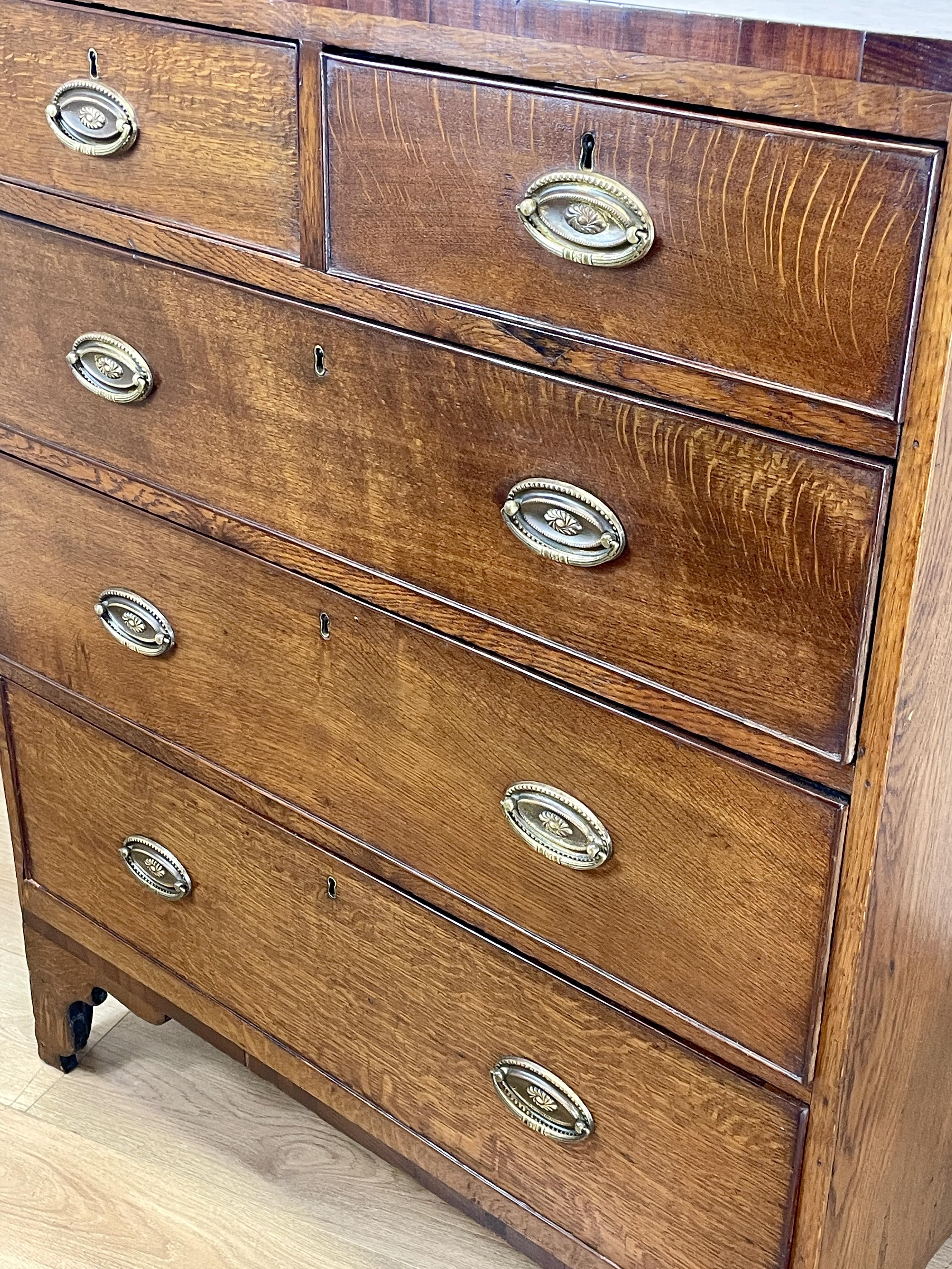 Wooden dresser with multiple drawers and metal handles on a light wooden floor.