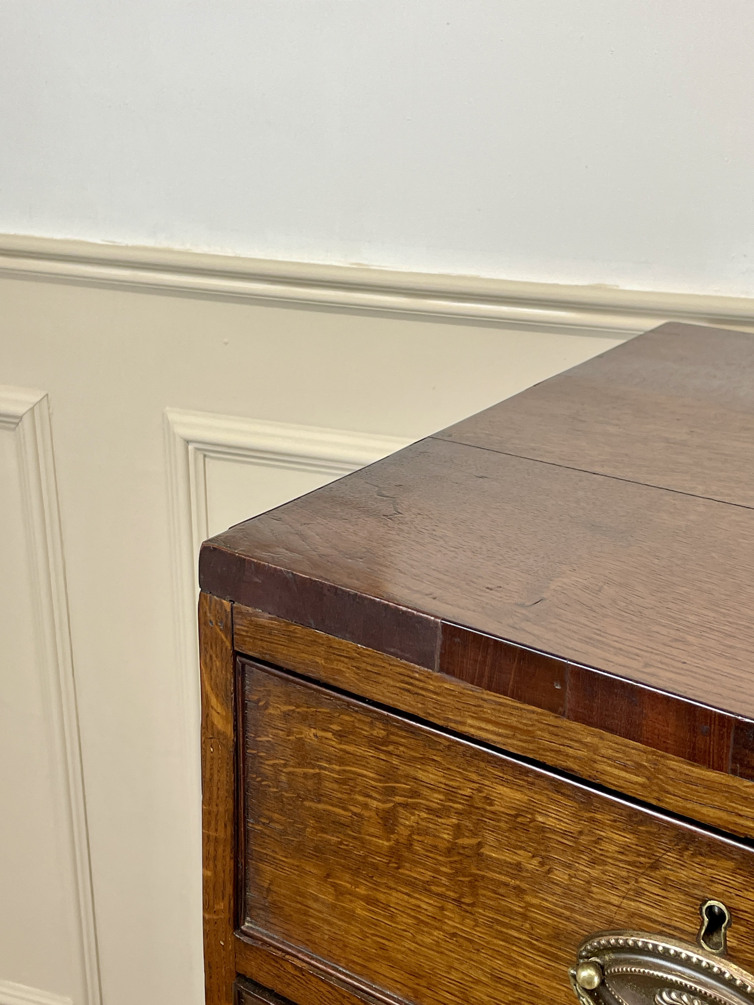 Wooden dresser with a metal handle against a white wall.