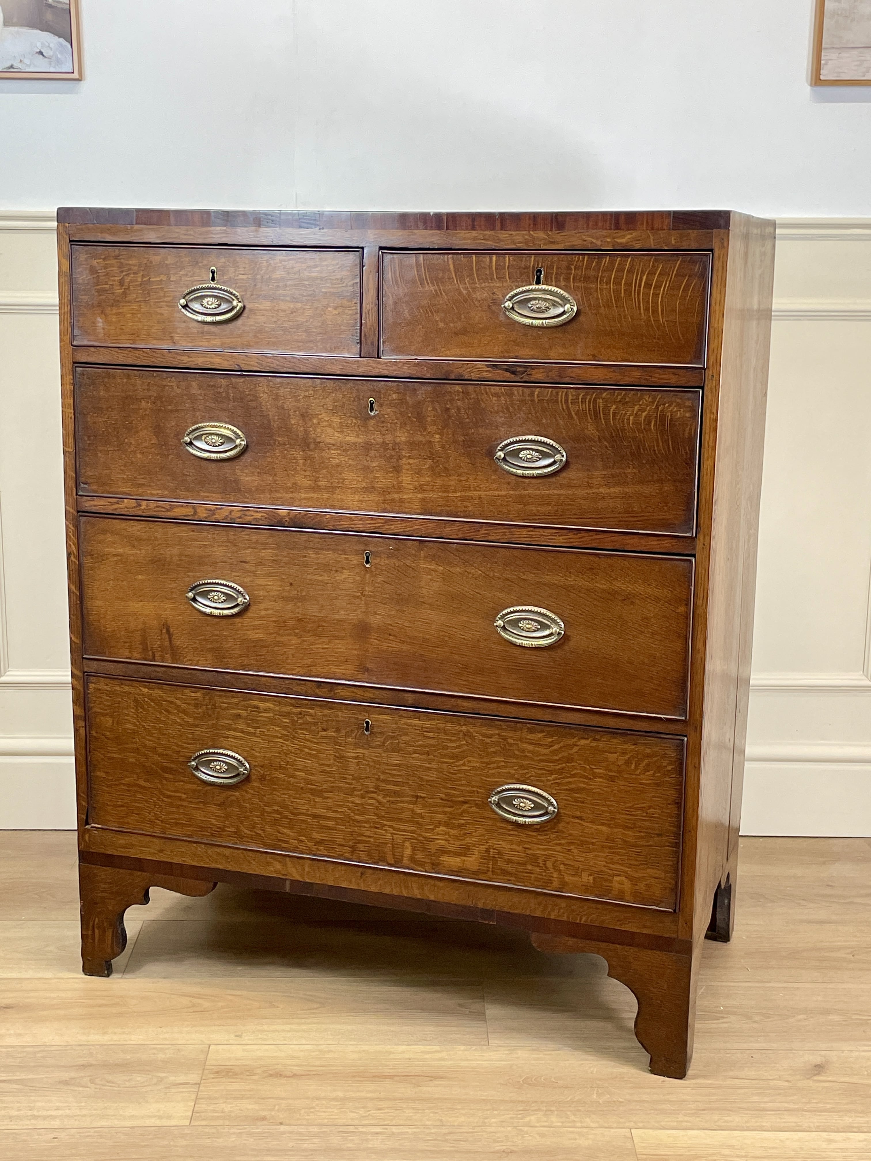 Wooden dresser with four drawers and metal handles on a wooden floor.