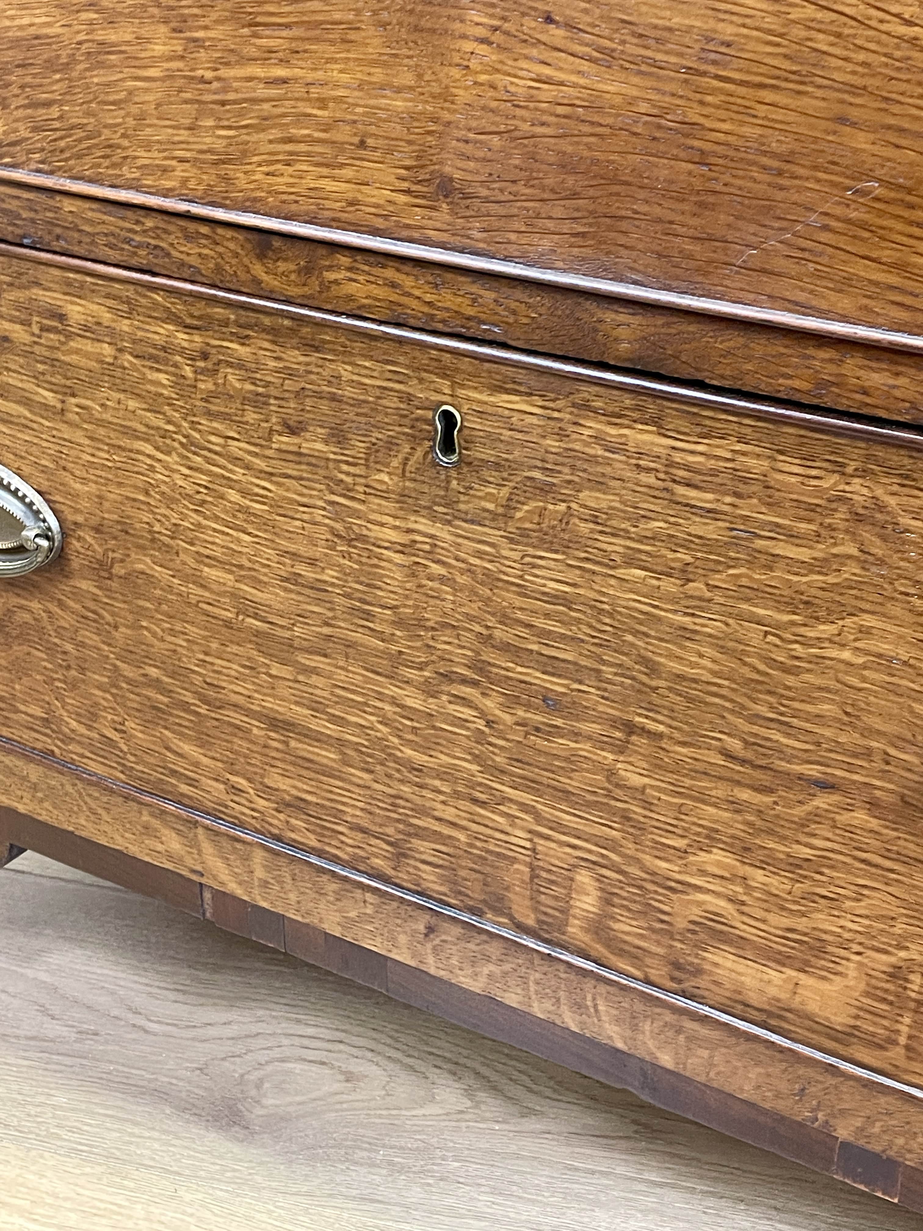 Close-up of a wooden dresser with a metal handle on a light wood floor.