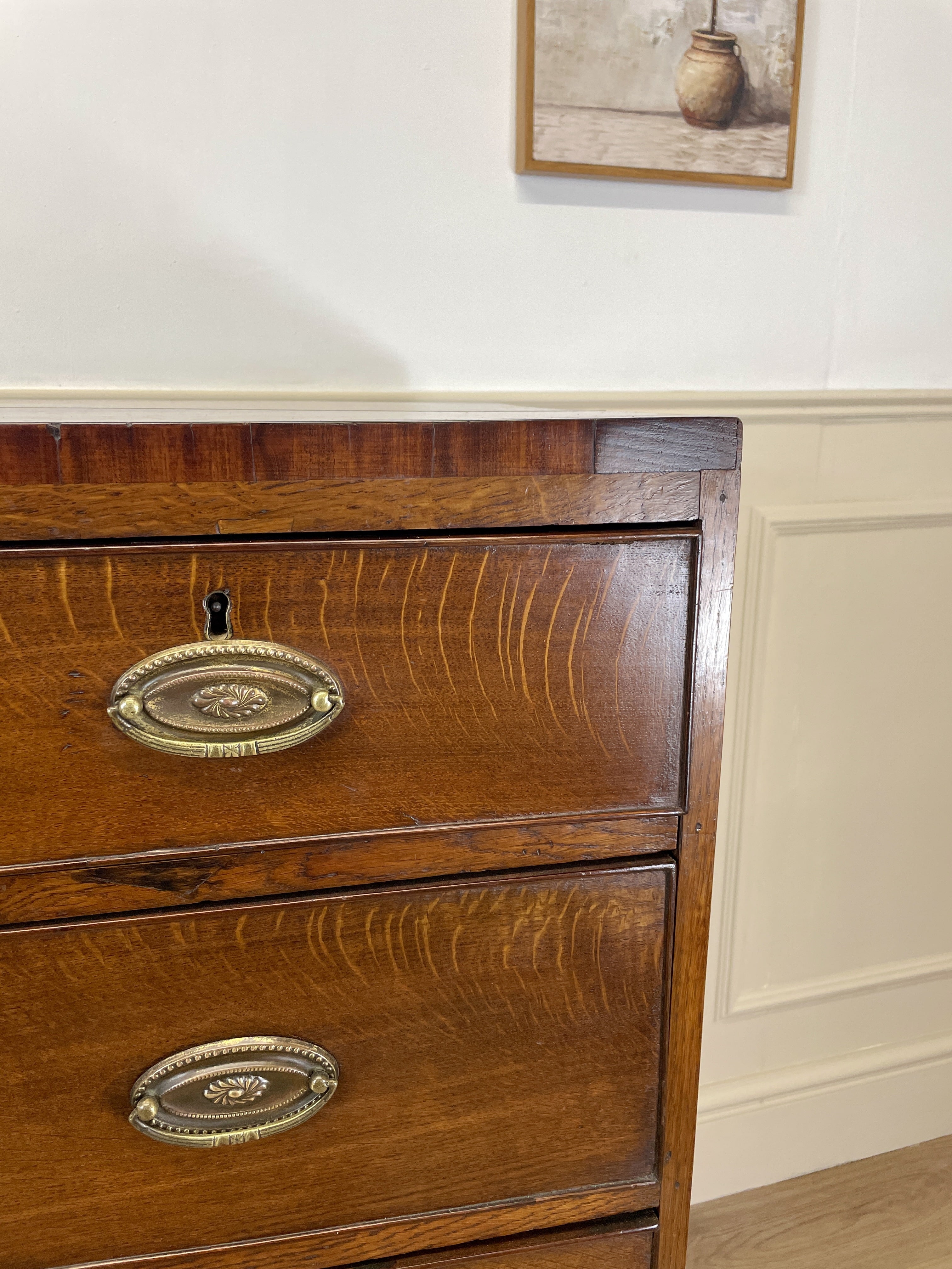 Wooden dresser with brass handles on a white wall background