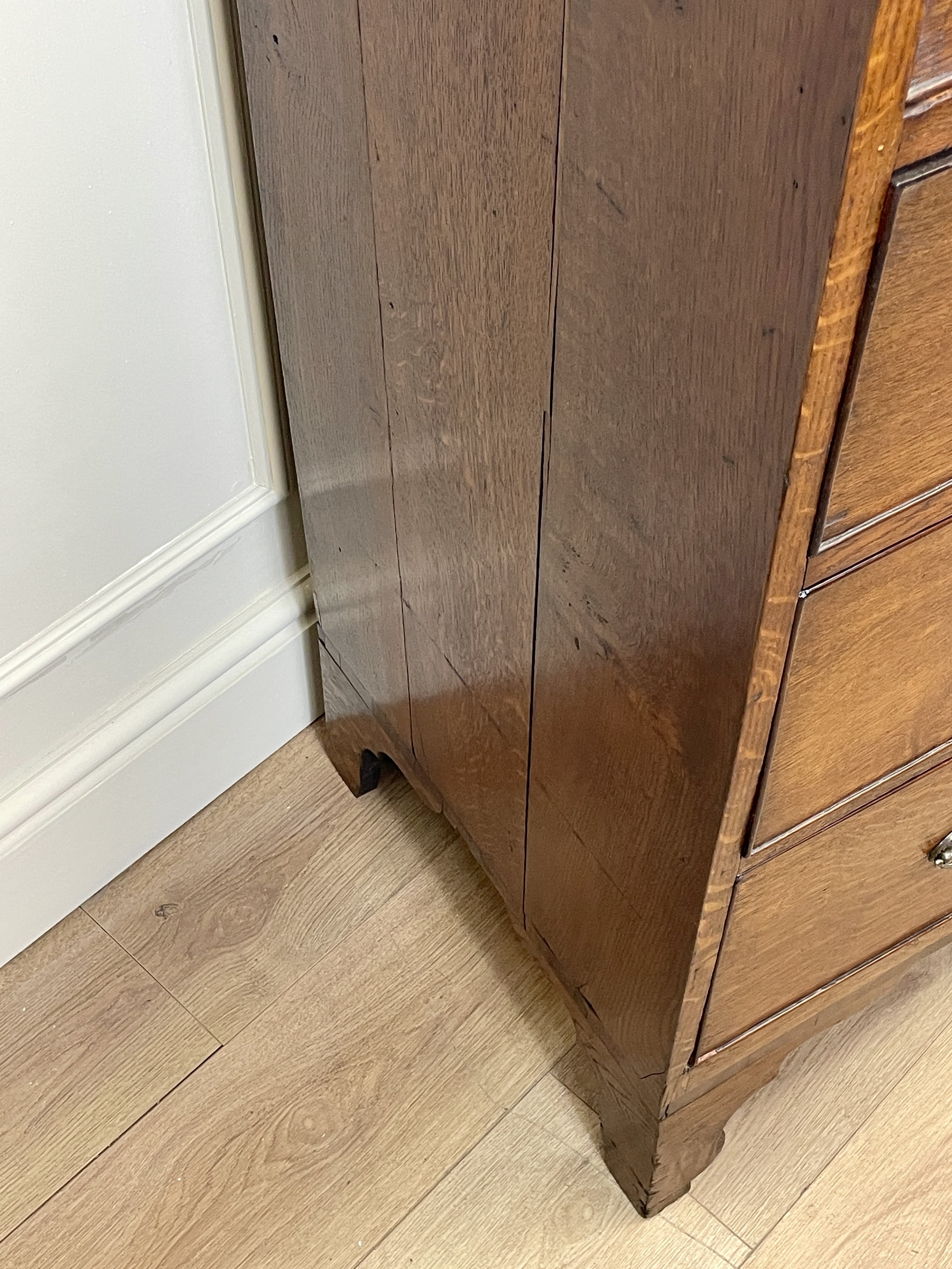 Wooden cabinet on a wooden floor with white baseboard