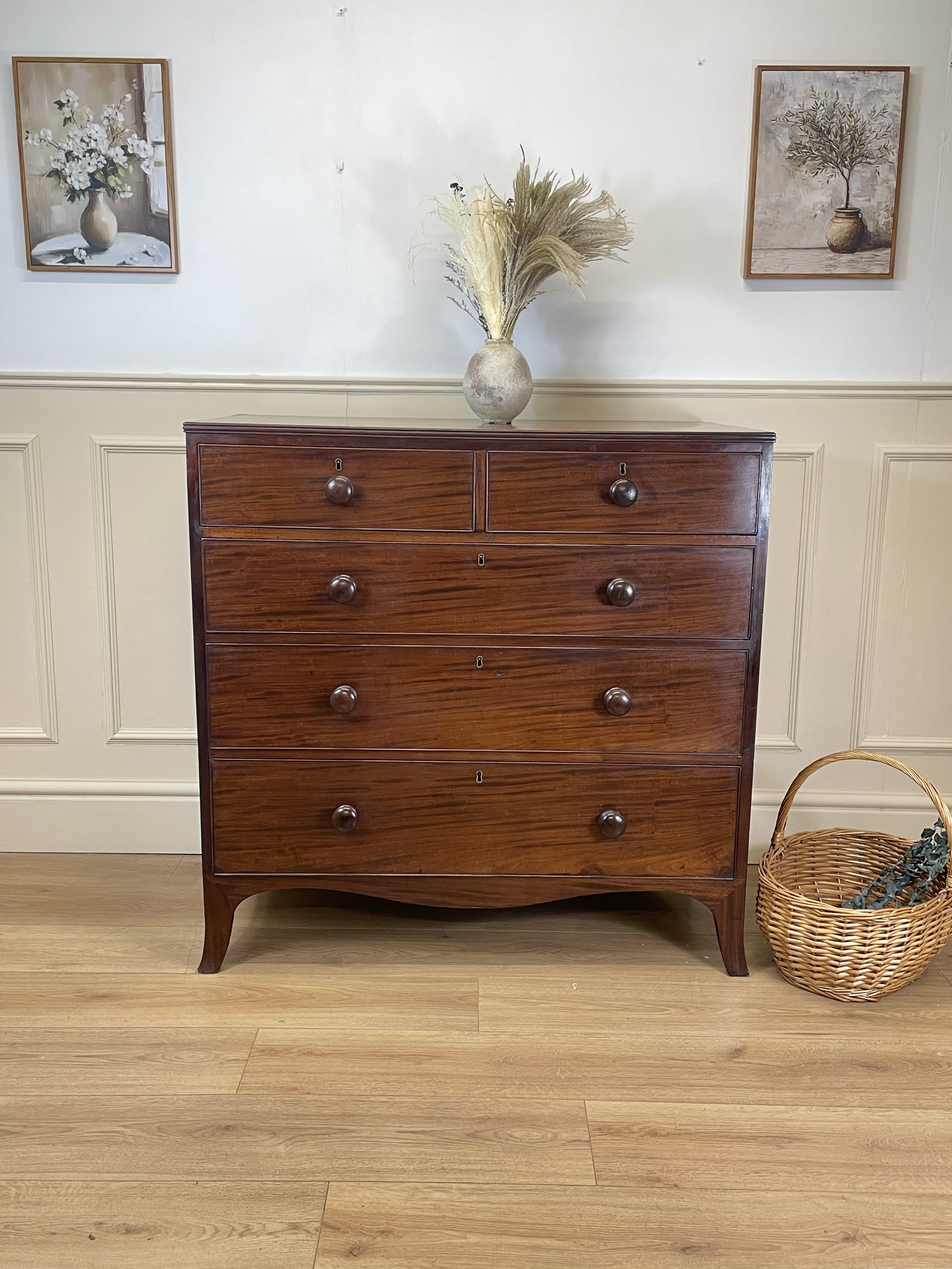 Wooden dresser with decorative items against a wall with framed pictures.