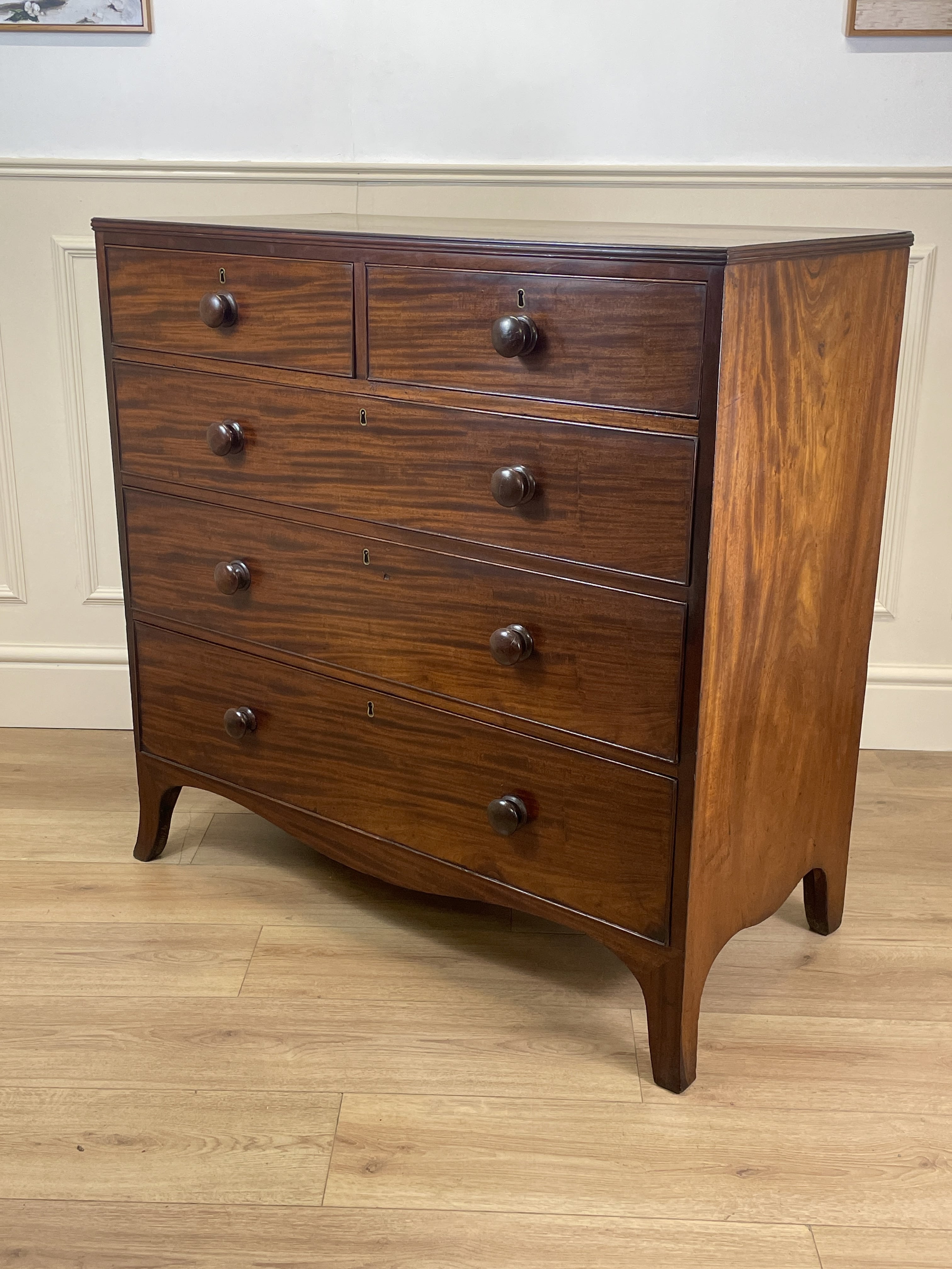 Wooden dresser with multiple drawers on a wooden floor.