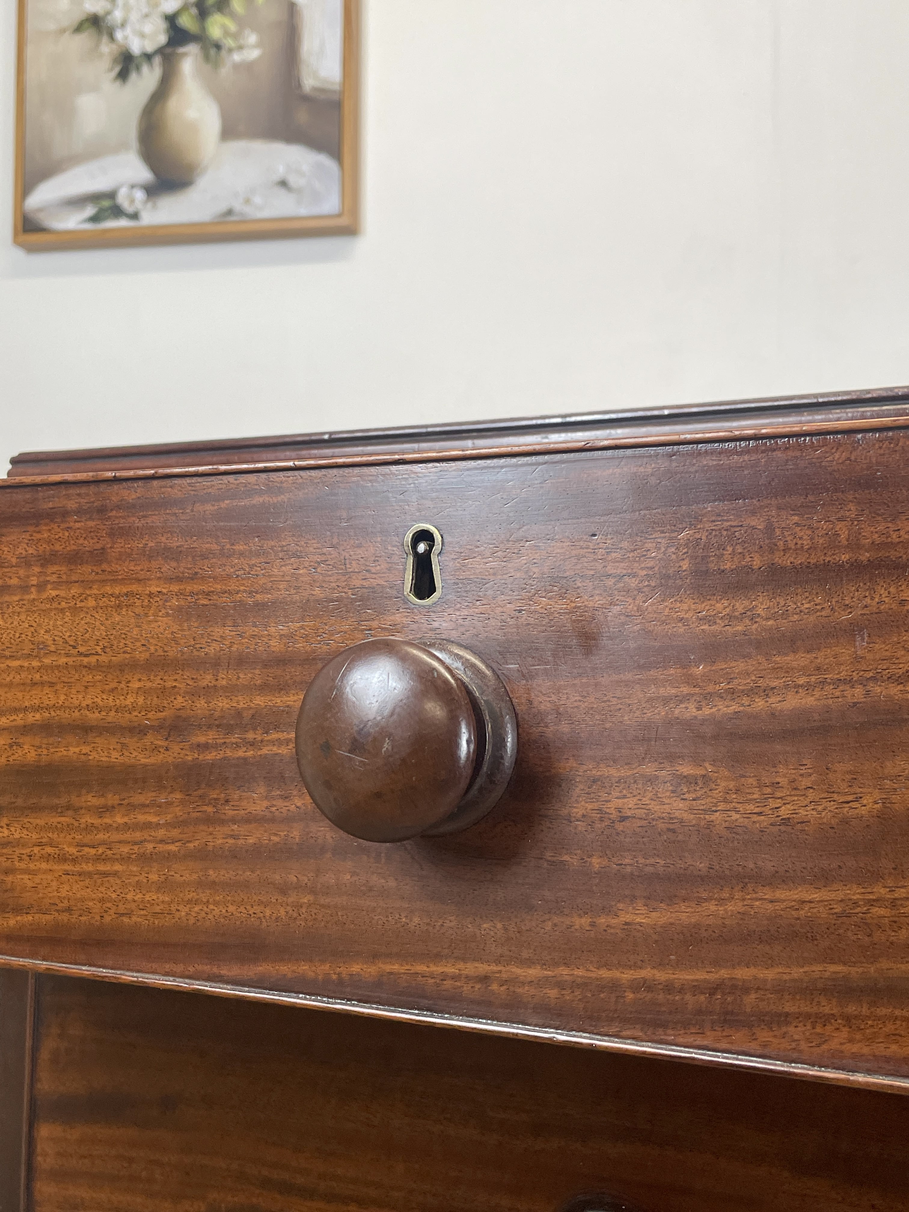 Close-up of a wooden drawer with a knob and lock, with a blurred background.