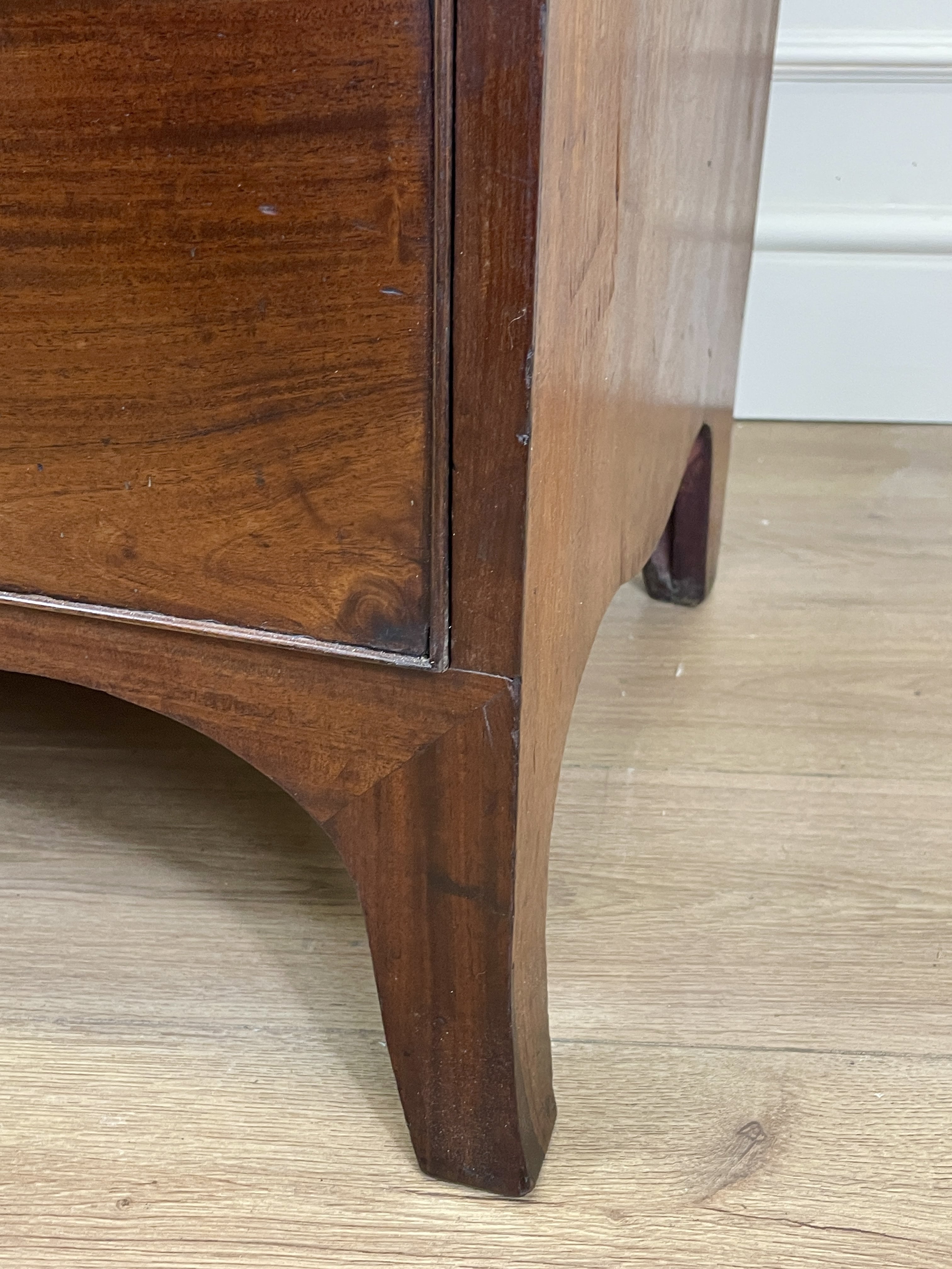 Close-up of a wooden furniture leg on a light wood floor.