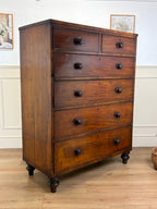 Wooden dresser with multiple drawers on a wooden floor.