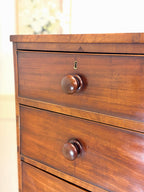 Wooden dresser with two drawers and brass handles on a blurred background