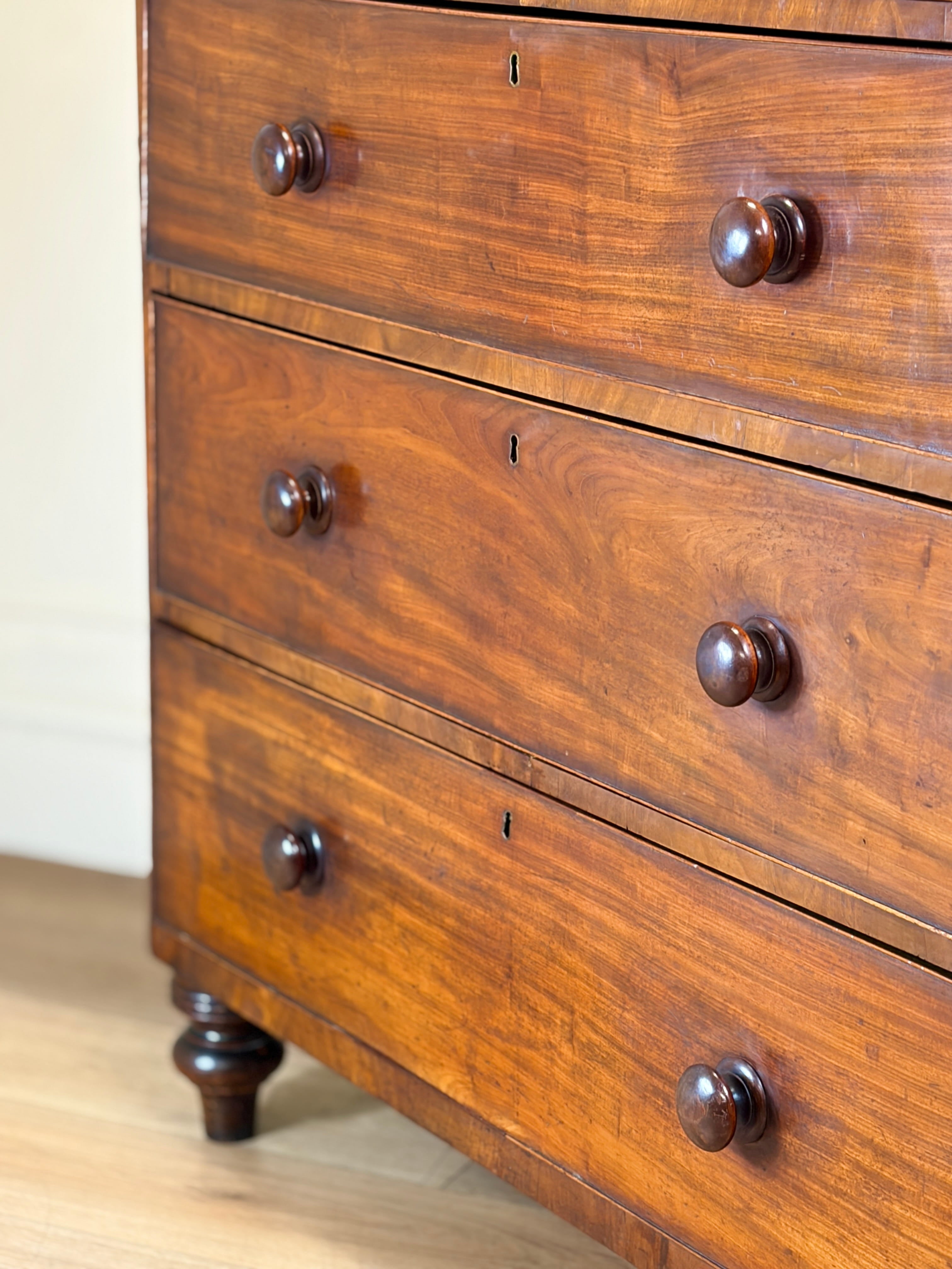 Close-up of a wooden dresser with four drawers and metal handles.