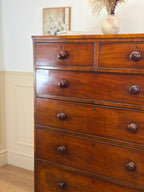 Wooden dresser with multiple drawers and wooden floor.