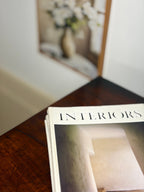 Open book titled 'Interiors' on a wooden surface with a blurred background