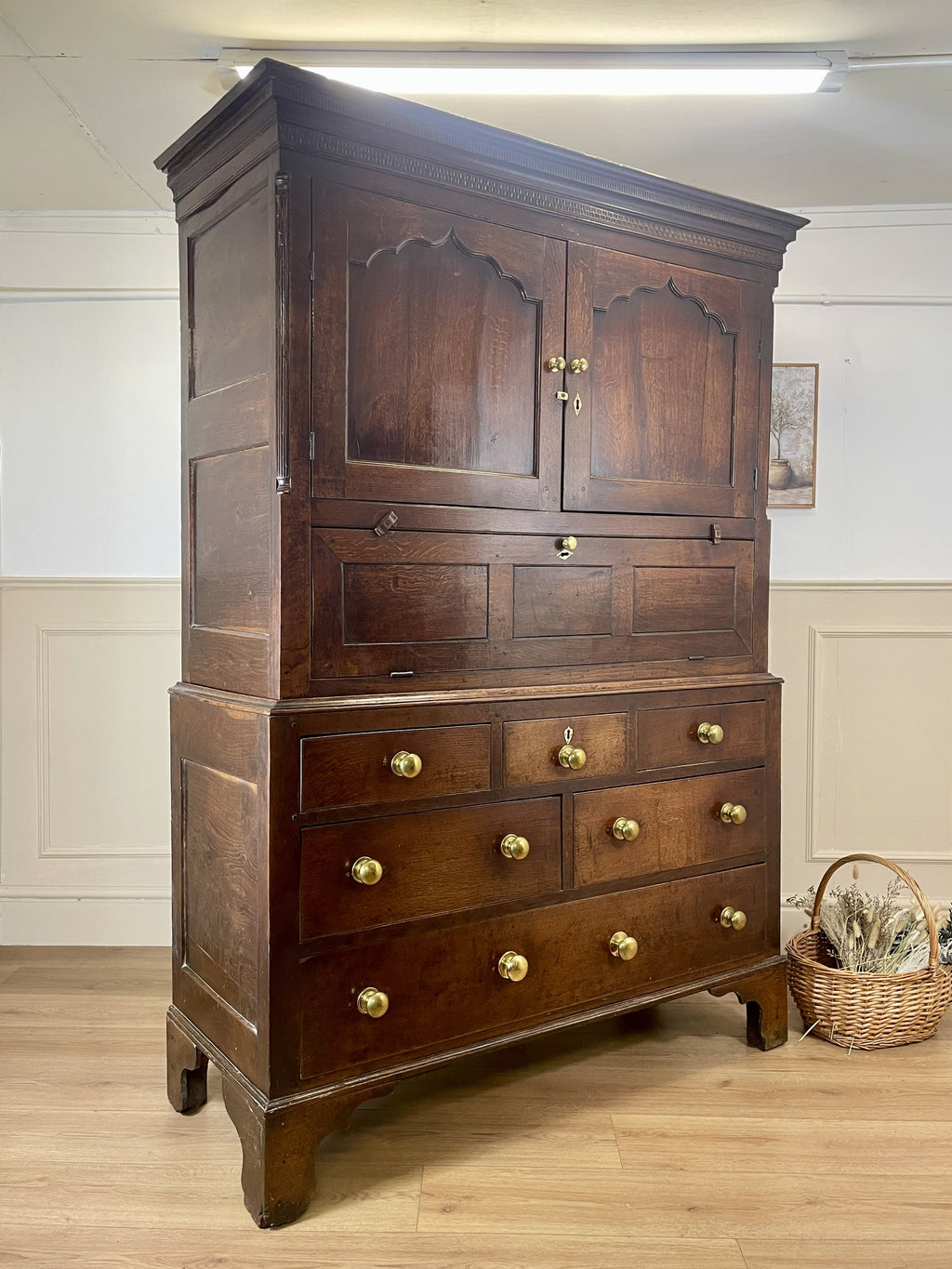 Wooden wardrobe with multiple drawers and cupboards on a wooden floor.