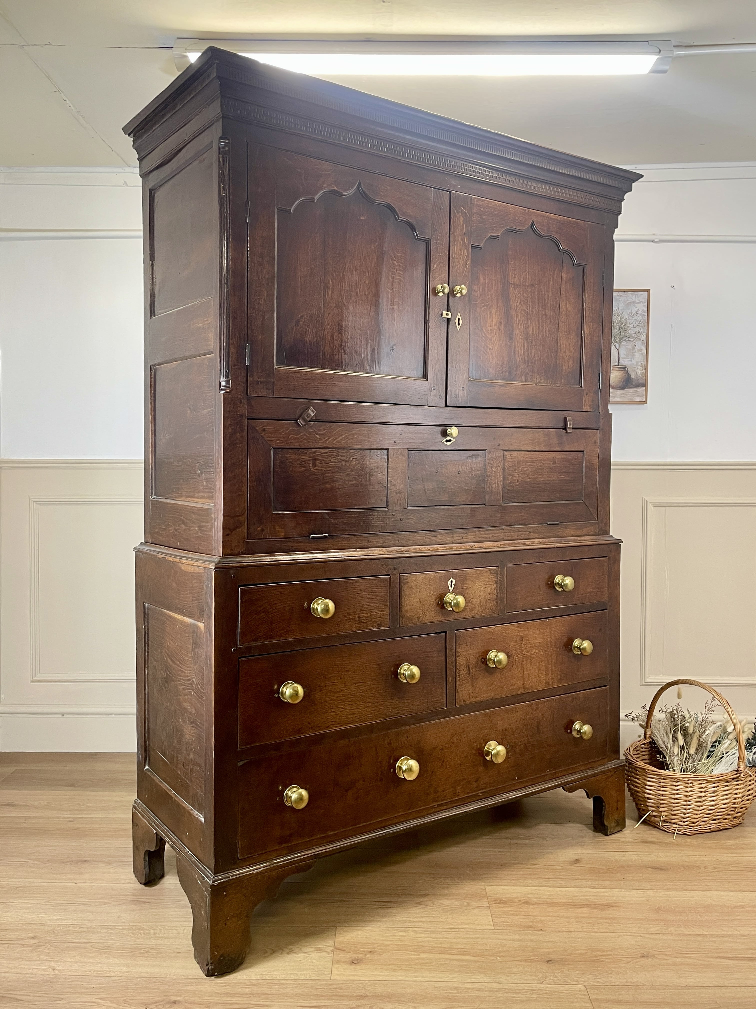 Wooden wardrobe with multiple drawers and cupboards on a wooden floor.