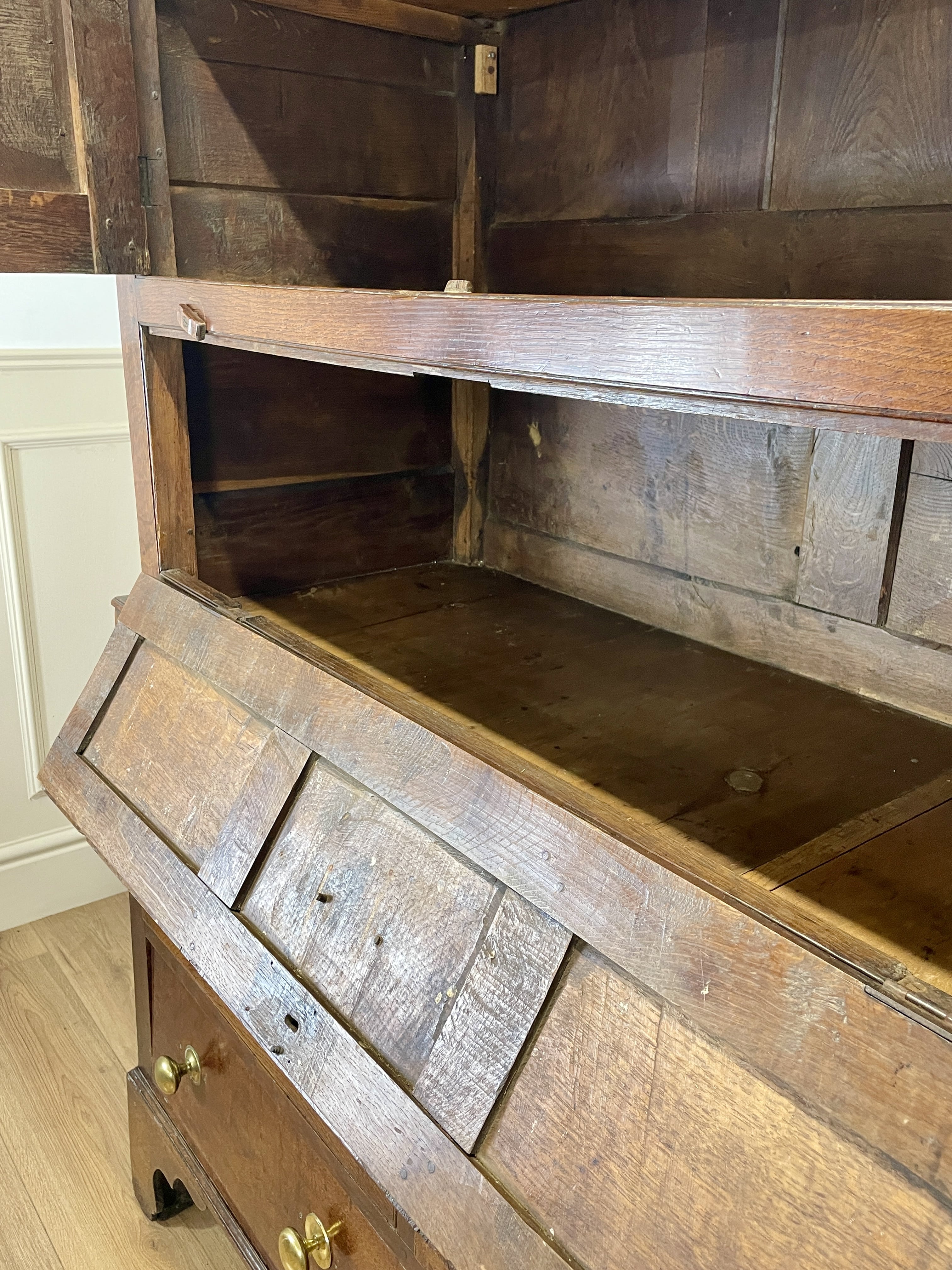 Wooden dresser with open shelves and drawers in a room with white walls and wooden floor.