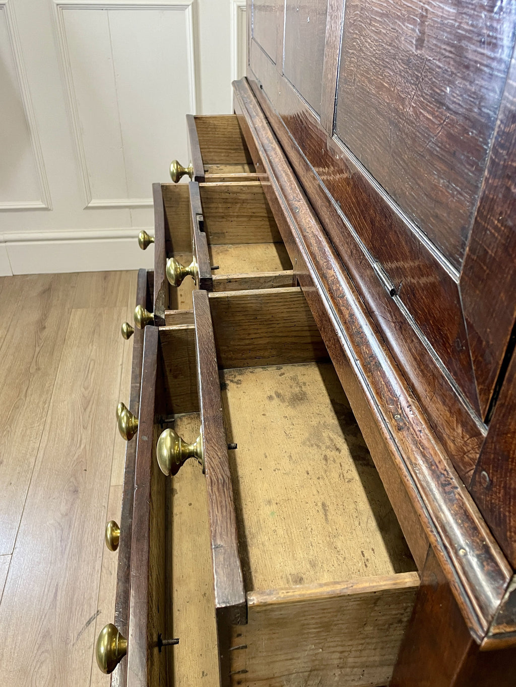 Wooden dresser with open drawers on a wooden floor.