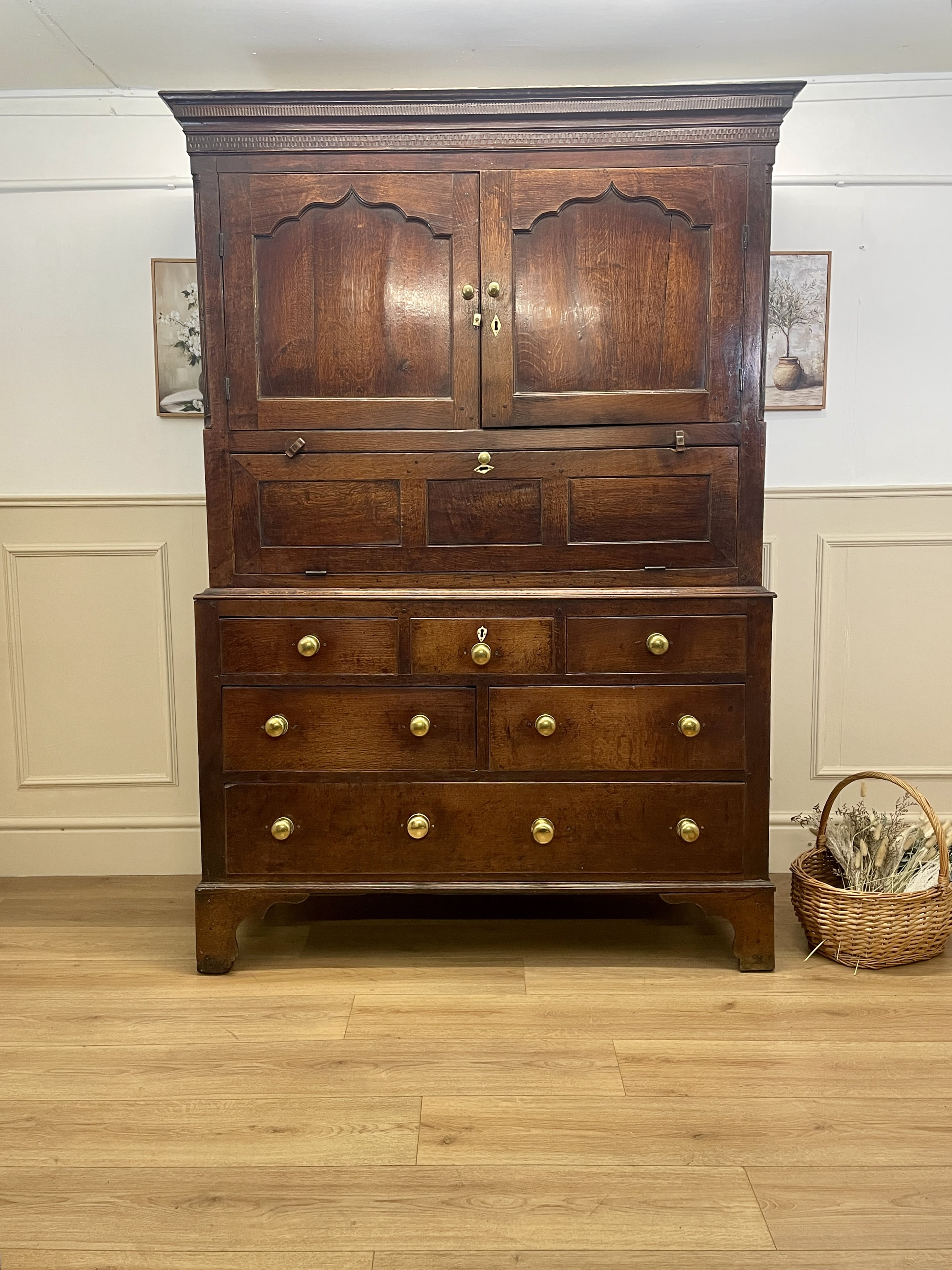 Wooden wardrobe with multiple drawers and doors in a room with a basket on the floor.