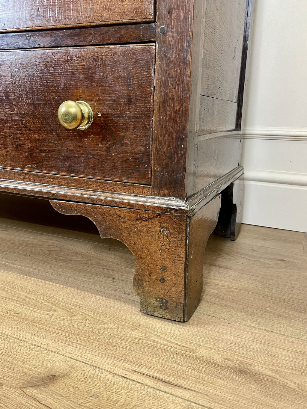 Wooden dresser with a gold handle on a wooden floor.