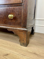 Wooden dresser with a gold handle on a wooden floor.