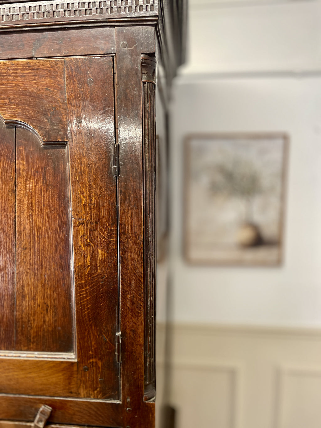 Close-up of a wooden cabinet with a blurred painting in the background