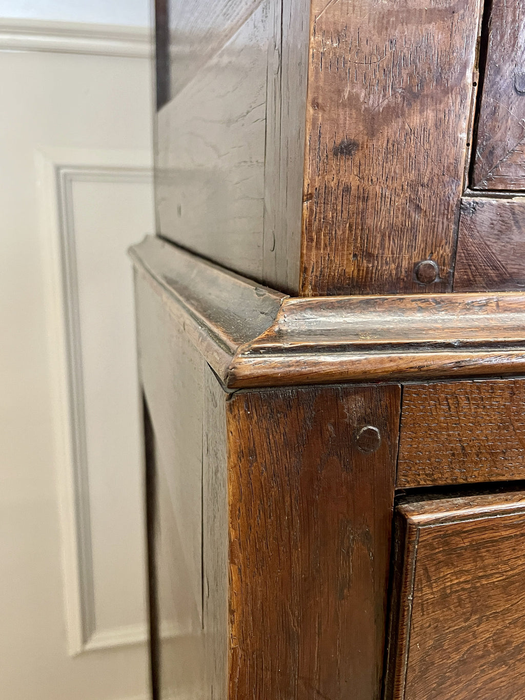 Close-up of a wooden cabinet corner with a neutral wall background