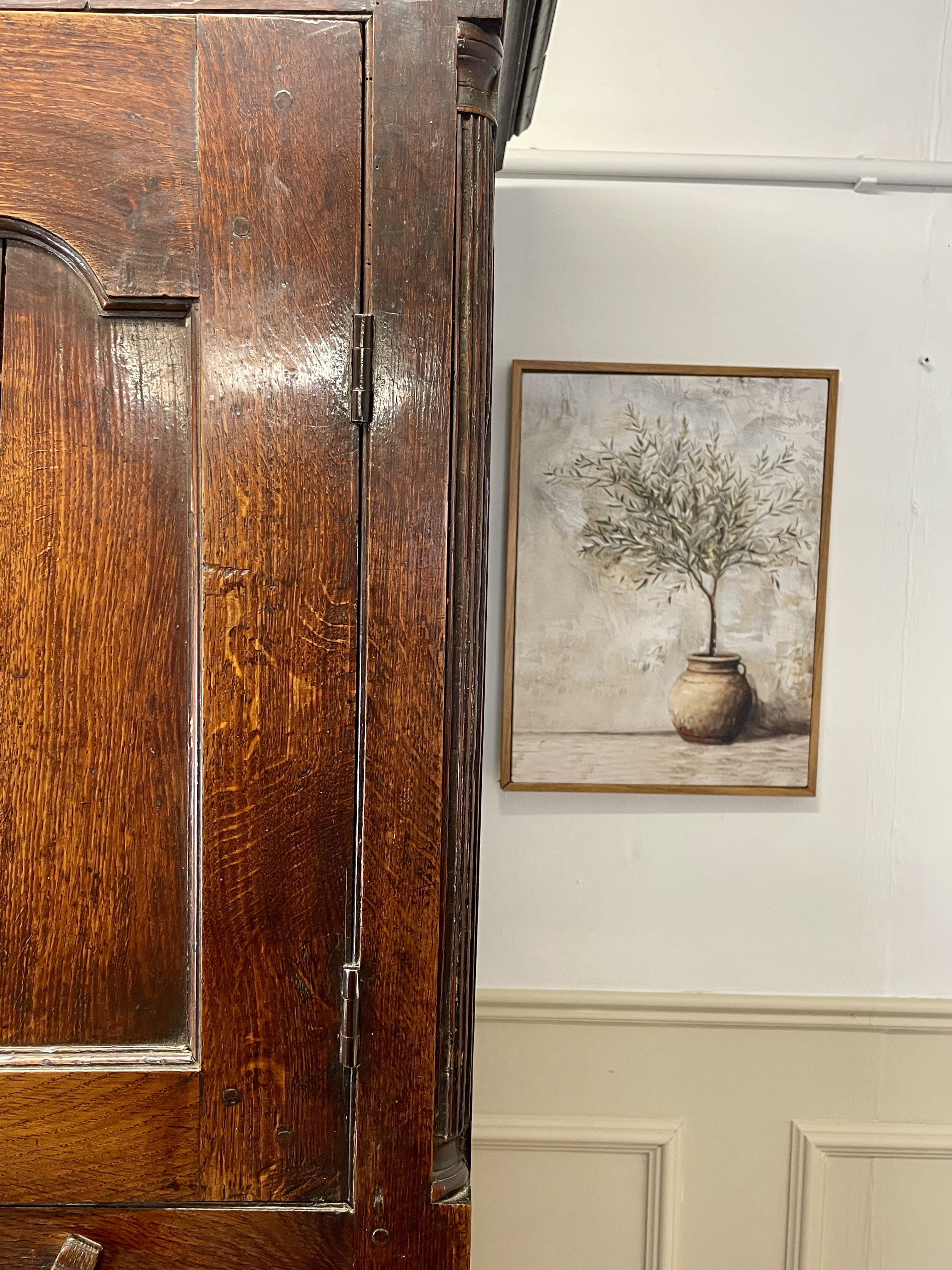 Wooden wardrobe with a framed artwork of a tree on a wall.