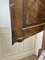 Close-up of a rustic wooden door frame against a white paneled wall.