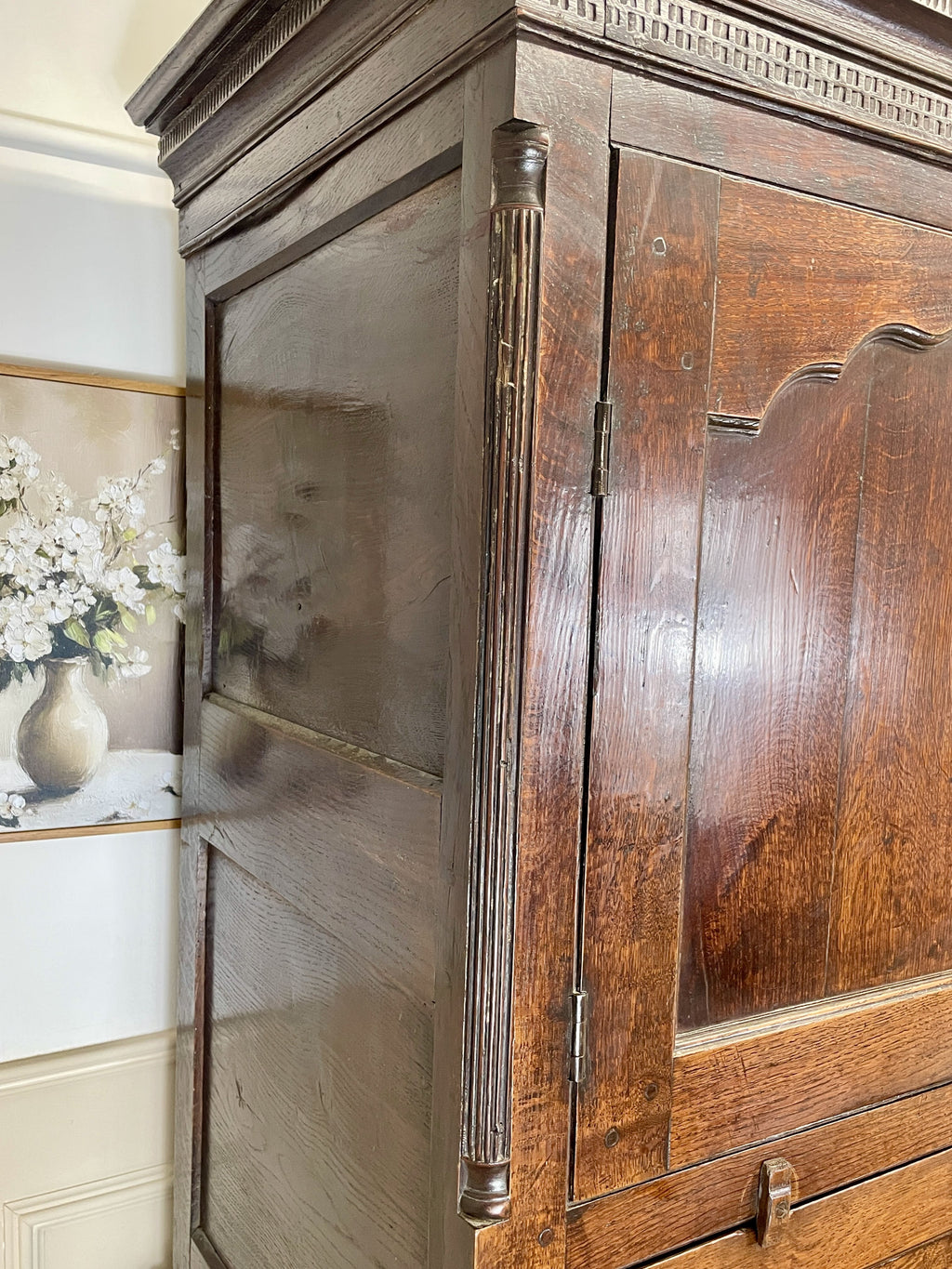 Wooden wardrobe with decorative elements in a room with a painting of flowers on the wall.