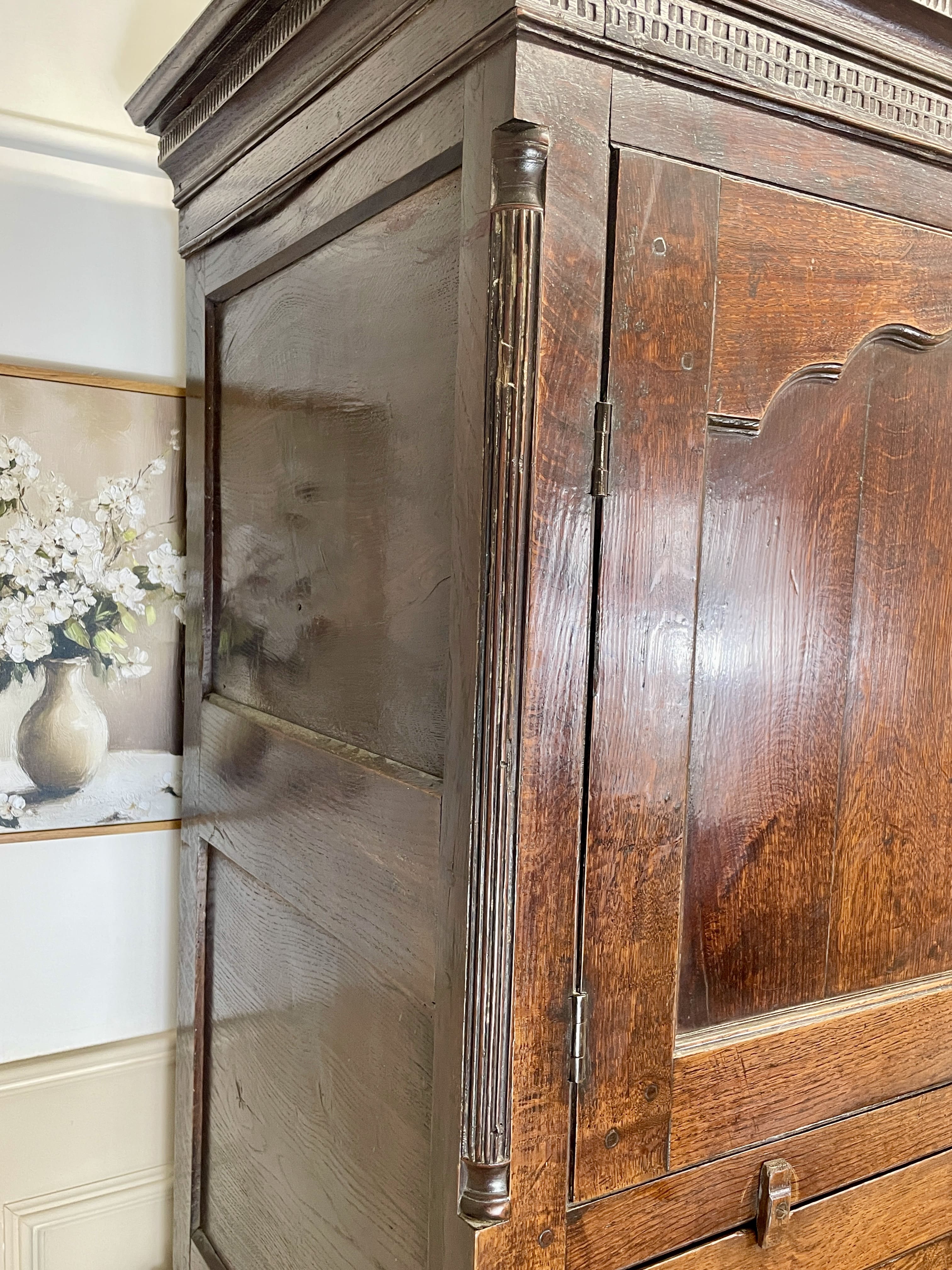 Wooden wardrobe with decorative elements in a room with a painting of flowers on the wall.