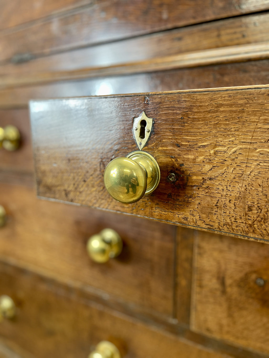 Close-up of a wooden drawer with brass handles and keyhole.