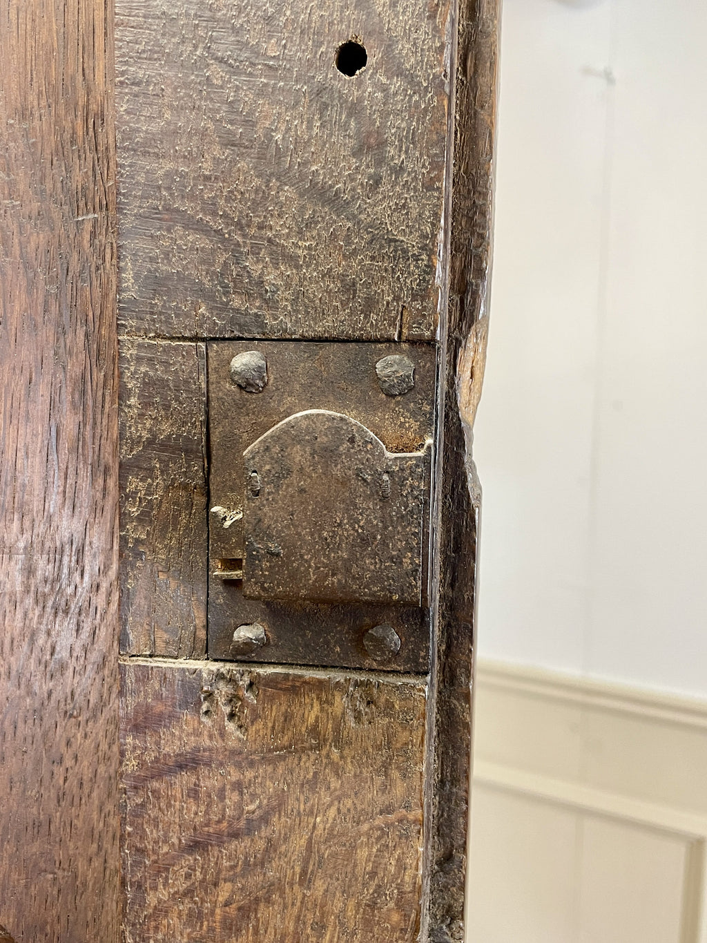 Close-up of a wooden door with a metal latch and a white wall in the background