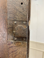 Close-up of a wooden door with a metal latch and a white wall in the background