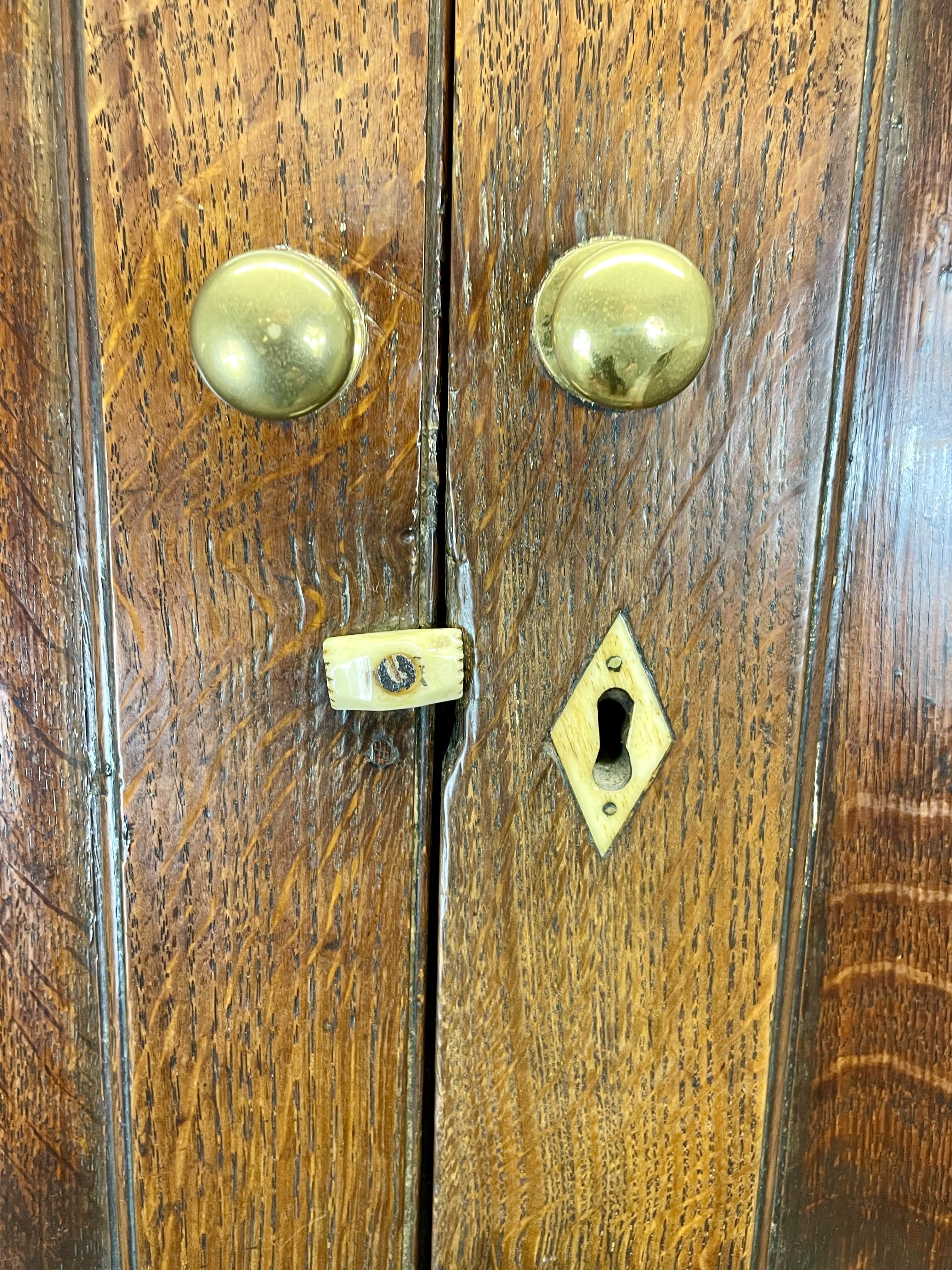 Close-up of a wooden door with brass handles and keyhole.