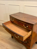 Wooden desk with open drawer against a white paneled wall.