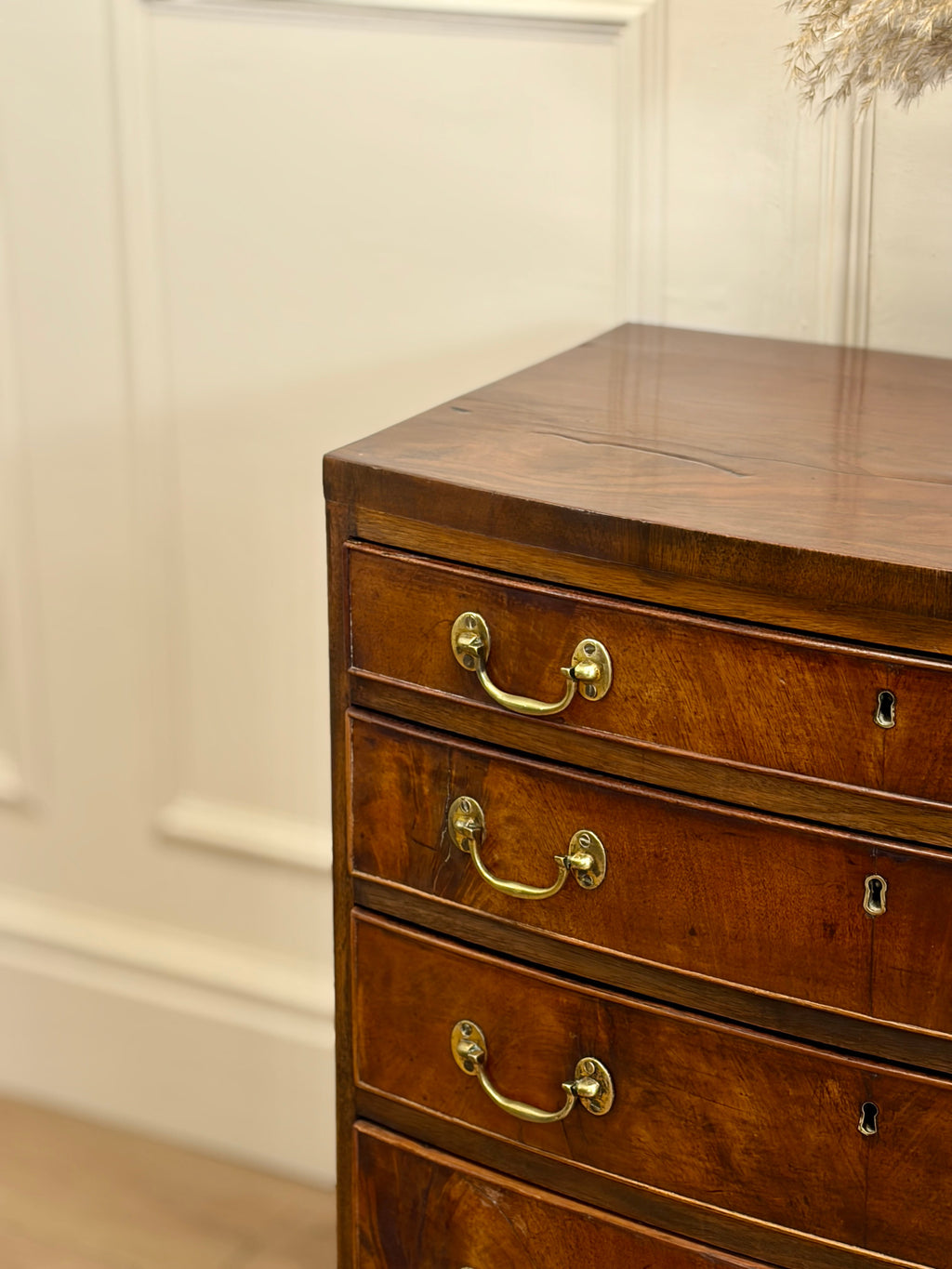 Wooden dresser with gold handles against a white wall