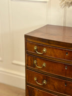 Wooden dresser with gold handles against a white wall