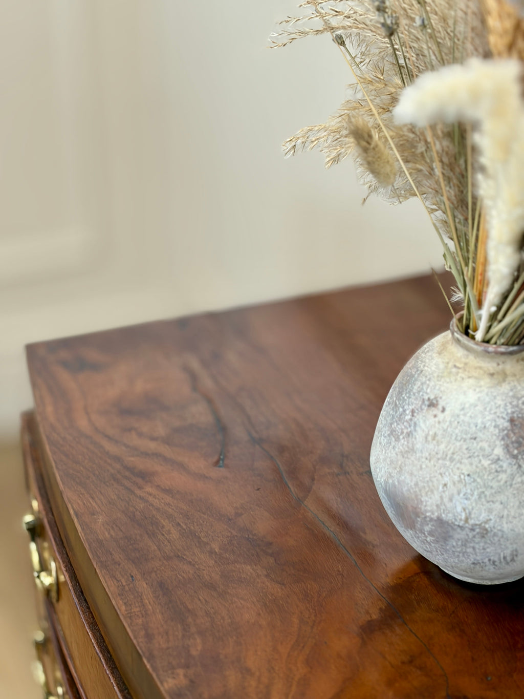 Decorative vase with dried plants on a wooden surface