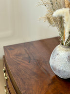 Decorative vase with dried plants on a wooden surface