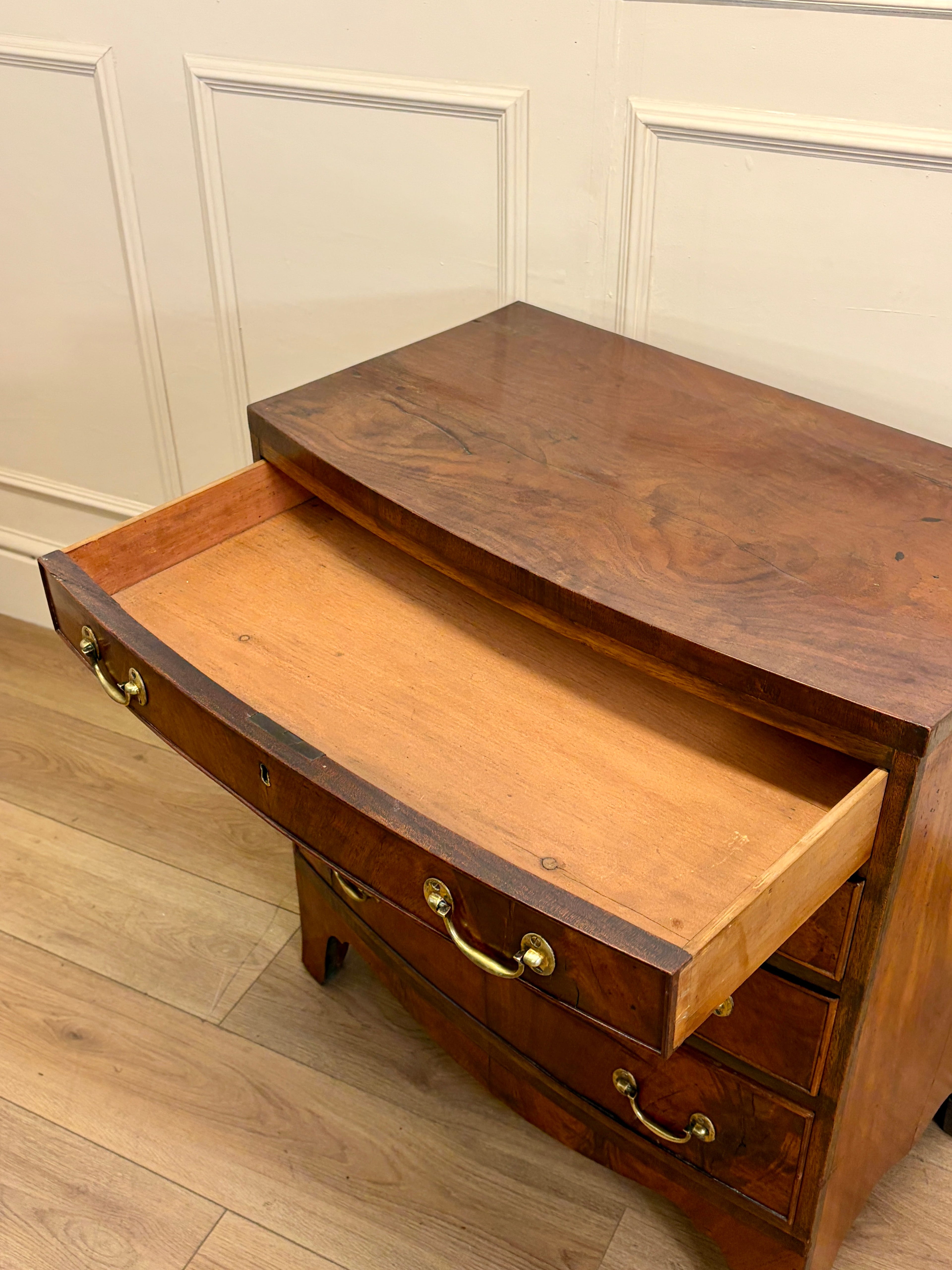 Wooden dresser with open drawer against a white paneled wall.
