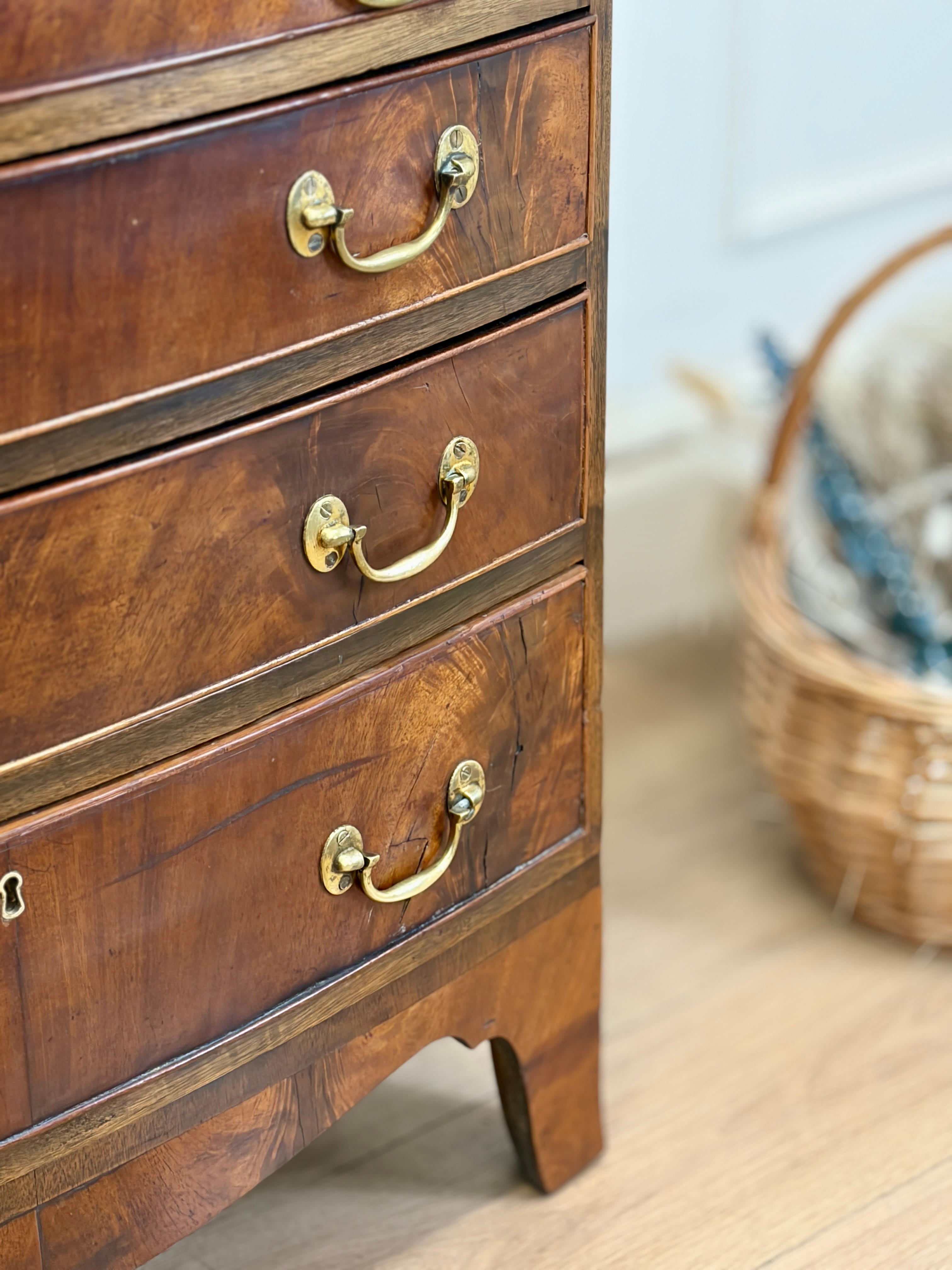 Wooden dresser with gold handles on a wooden floor, with a basket in the background.